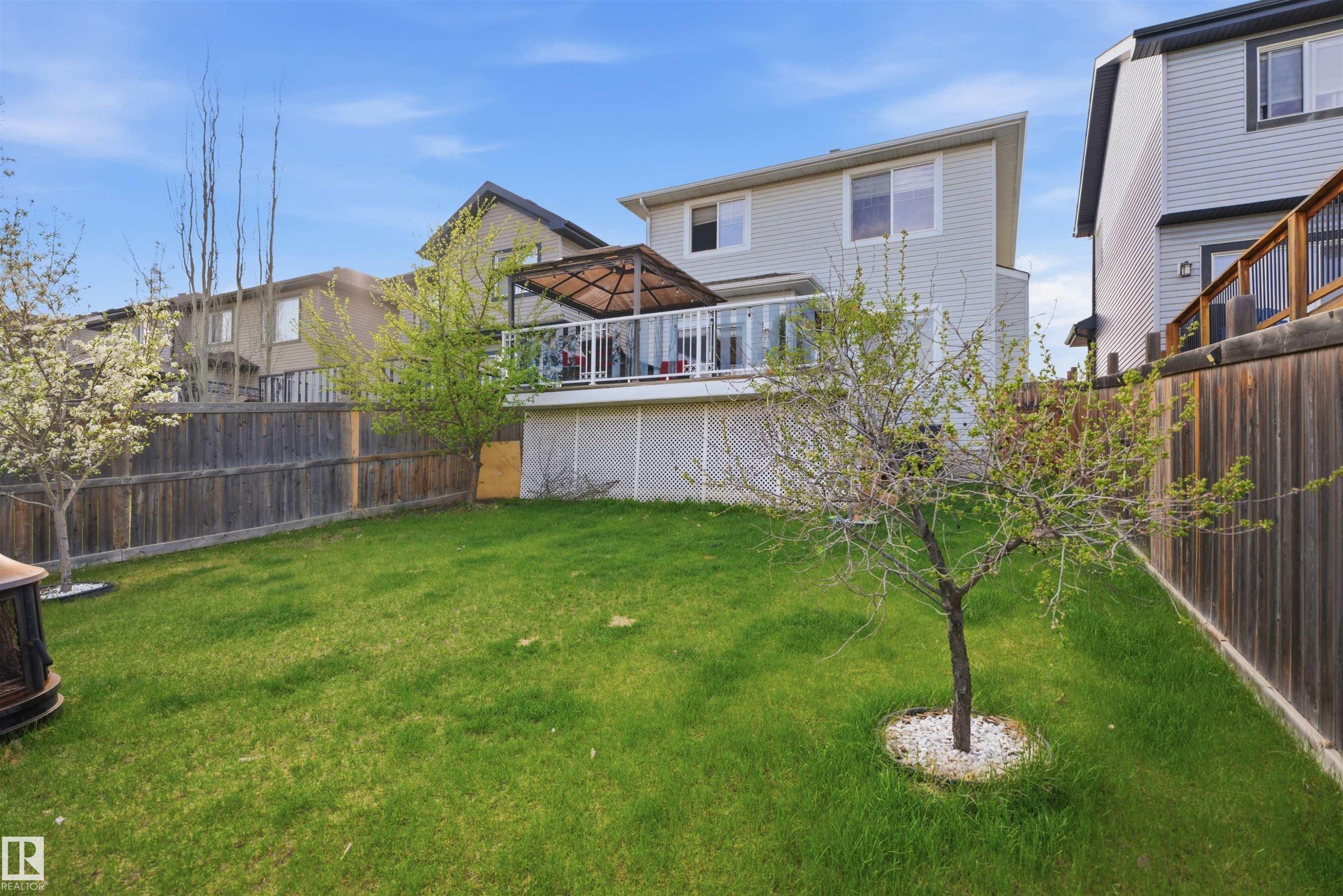 Expansive backyard featuring a manicured lawn, established trees, and a wooden privacy fence - 1453 Hays Way Nw, Edmonton, AB - Outdoor With Deck Patio Veranda