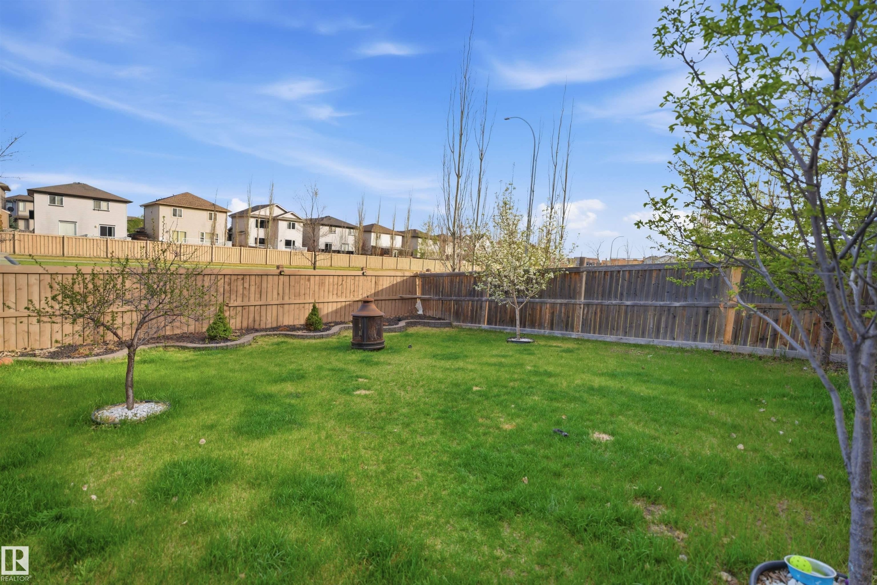 Expansive backyard featuring a lush lawn, mature trees, and a tall privacy fence - 1453 Hays Way Nw, Edmonton, AB - Outdoor With Backyard