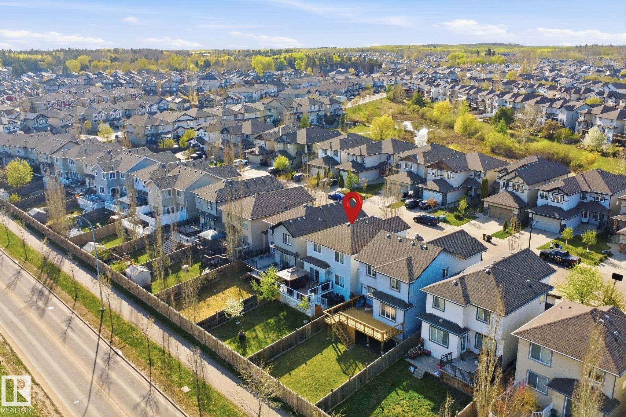 Contemporary two-story residence featuring a wood deck, fenced backyard, and surrounding residential landscape - 1453 Hays Way Nw, Edmonton, AB - Outdoor With View