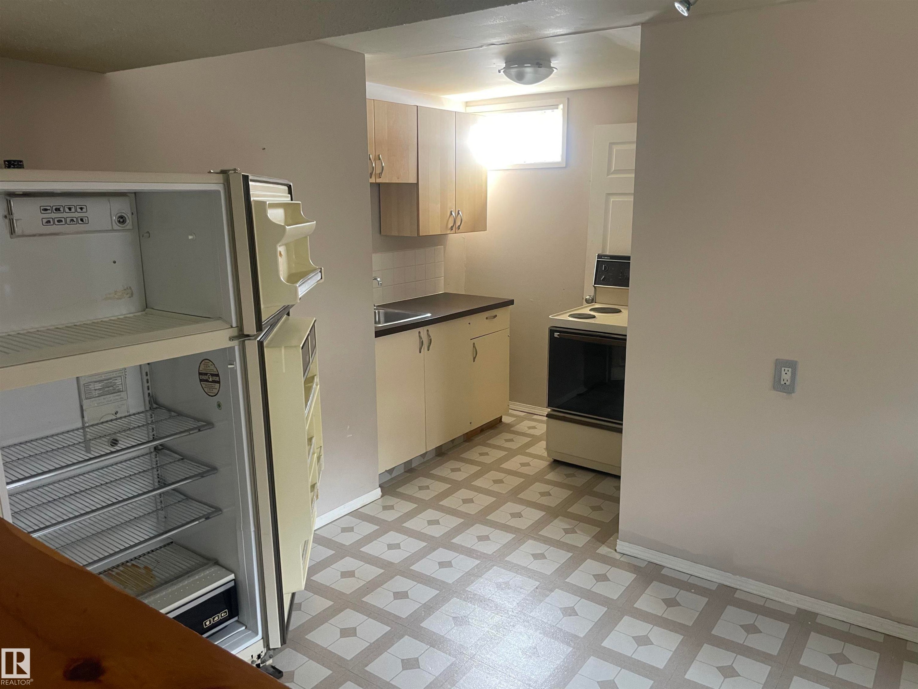 The kitchen features wood cabinetry, a sink with a dark countertop, a window providing natural light, and patterned flooring - 2629 129A Avenue, Edmonton, AB - Indoor Photo Showing Other Room