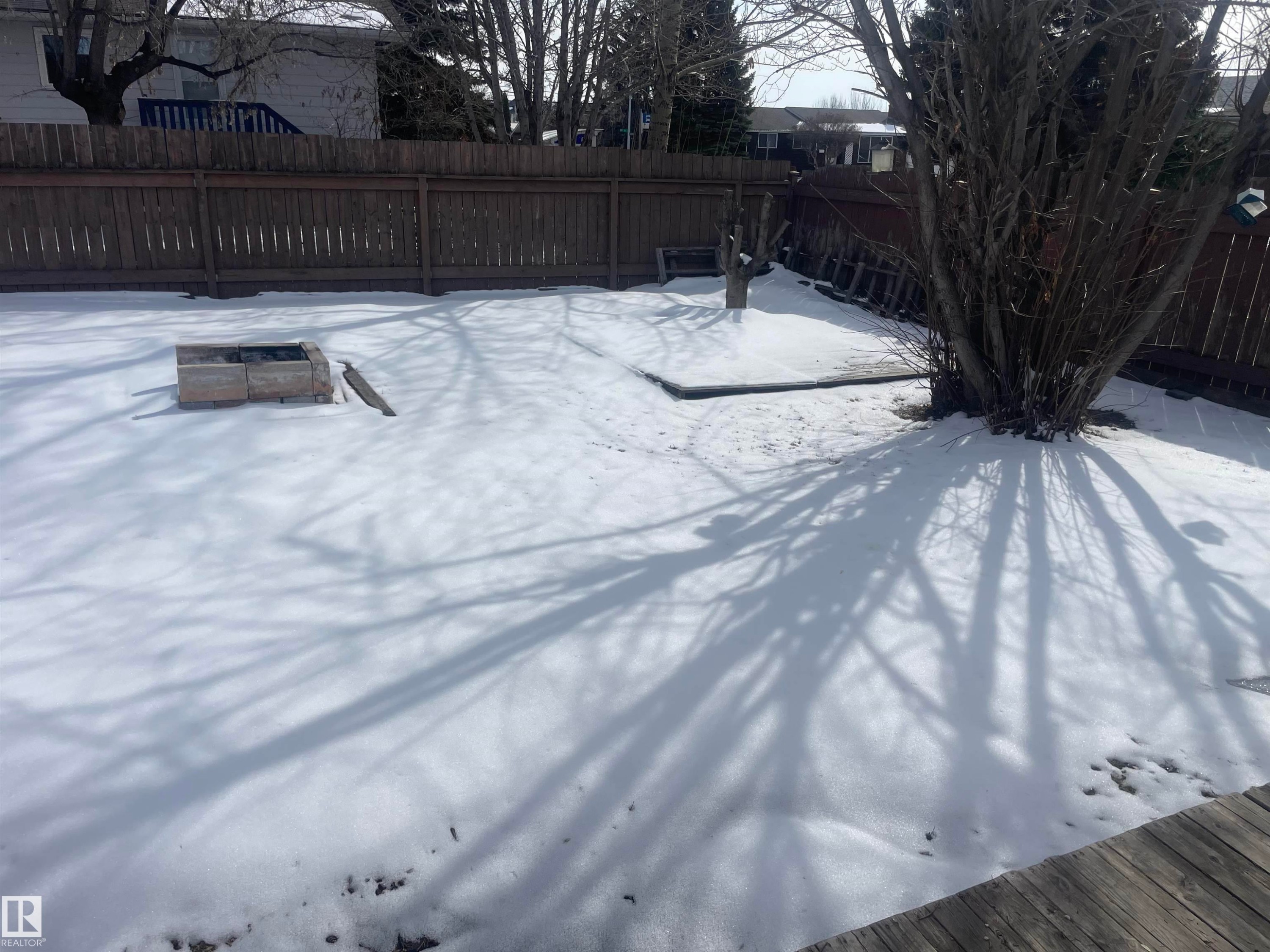 The property features a fenced yard with a fire pit and a mature tree, offering privacy and a space for outdoor activities - 2629 129A Avenue, Edmonton, AB - Outdoor
