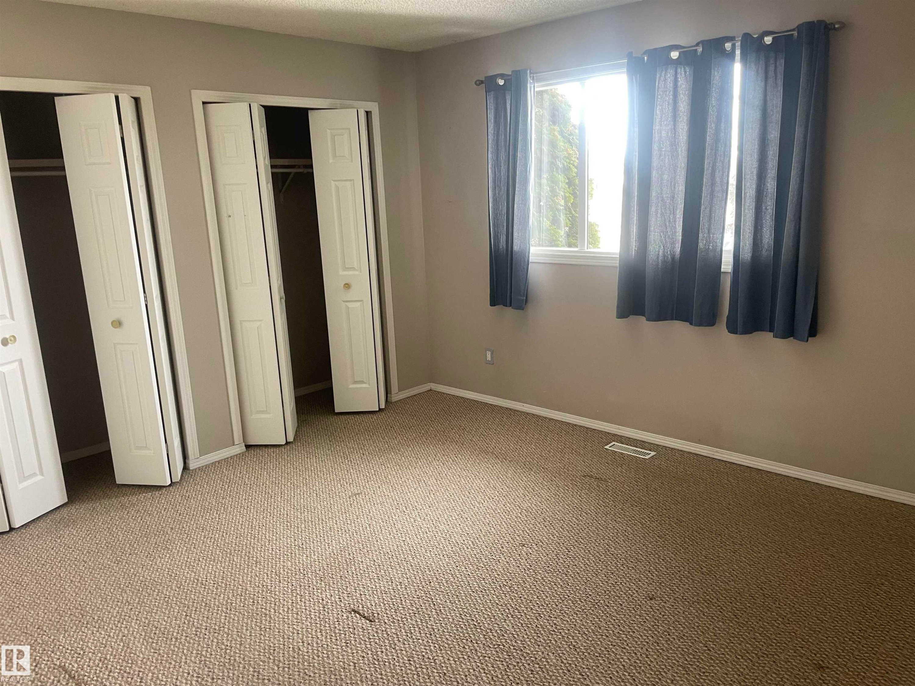 This room features light-colored walls, carpeted flooring, and a window with dark curtains - 2629 129A Avenue, Edmonton, AB - Indoor