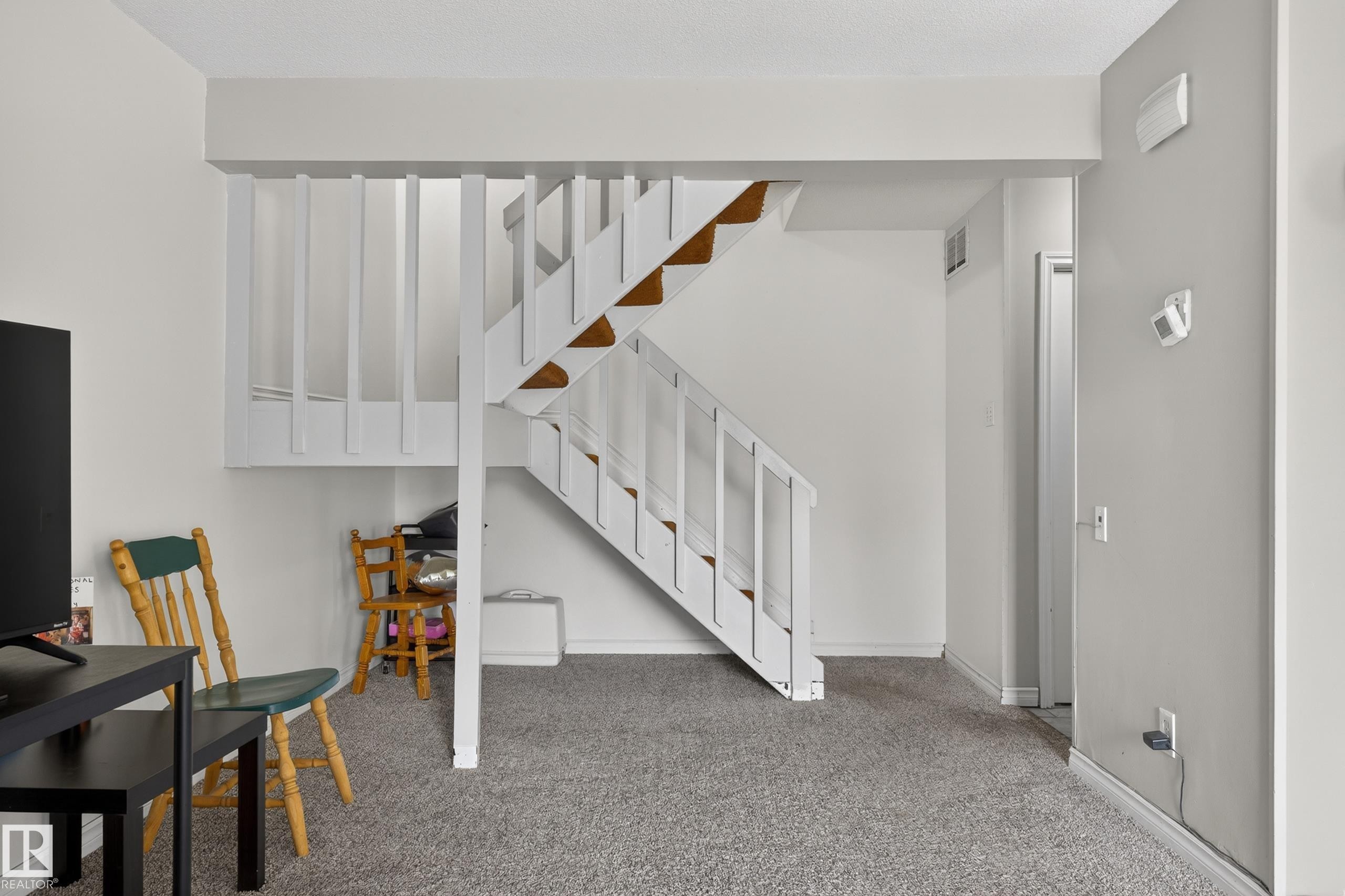 Interior staircase with white painted balusters and wood-finish treads, set against neutral wall tones - 26E Meadowlark Village, Edmonton, AB - Indoor Photo Showing Other Room