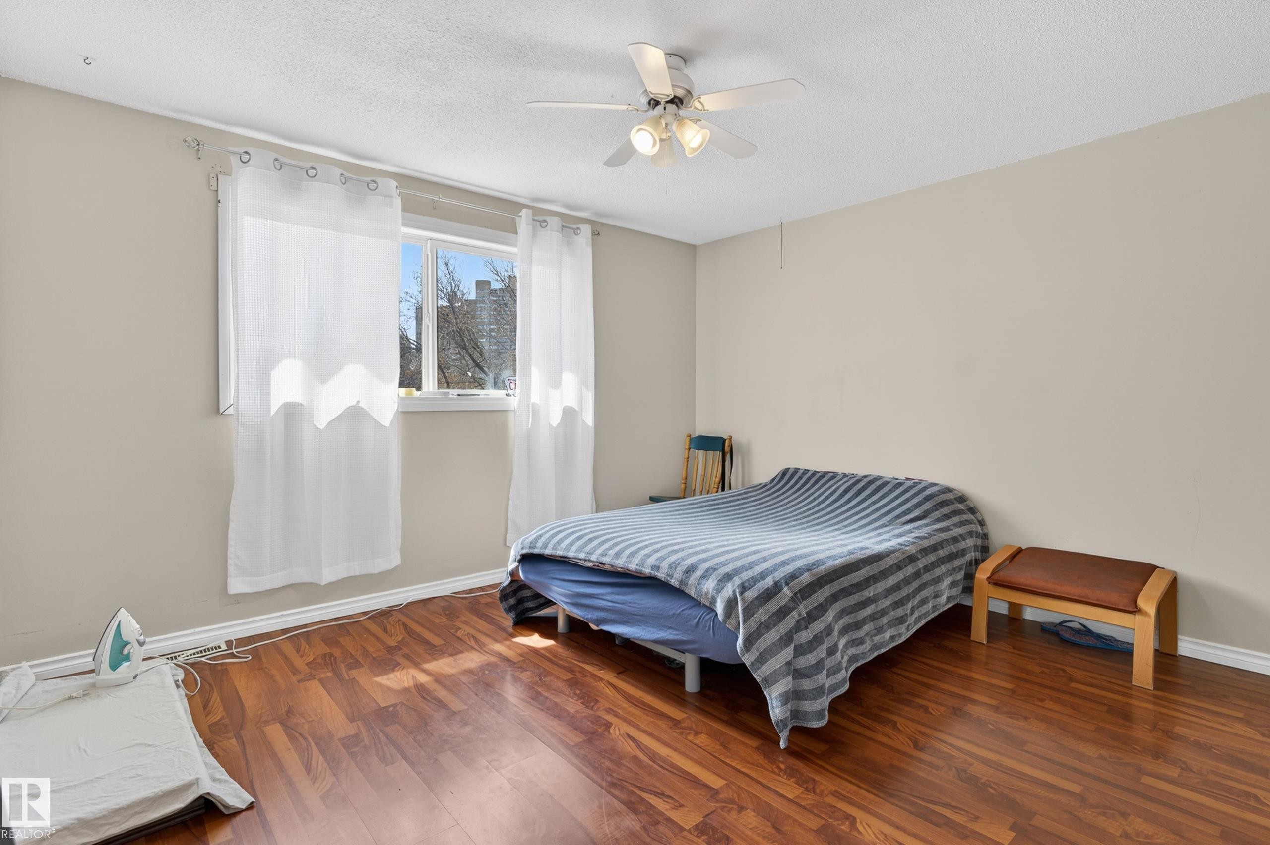 Room featuring wood-finish flooring, neutral wall paint, and a multi-pane window - 26E Meadowlark Village, Edmonton, AB - Indoor Photo Showing Bedroom