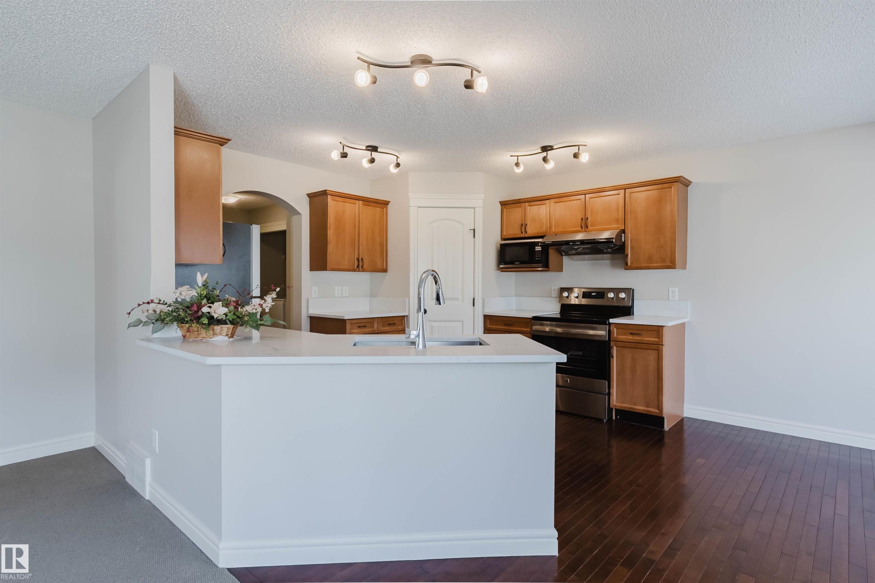 Kitchen featuring wood-finish cabinetry, stainless steel appliances, and light-toned countertops - 1140 115 Street, Edmonton, AB - Indoor Photo Showing Kitchen