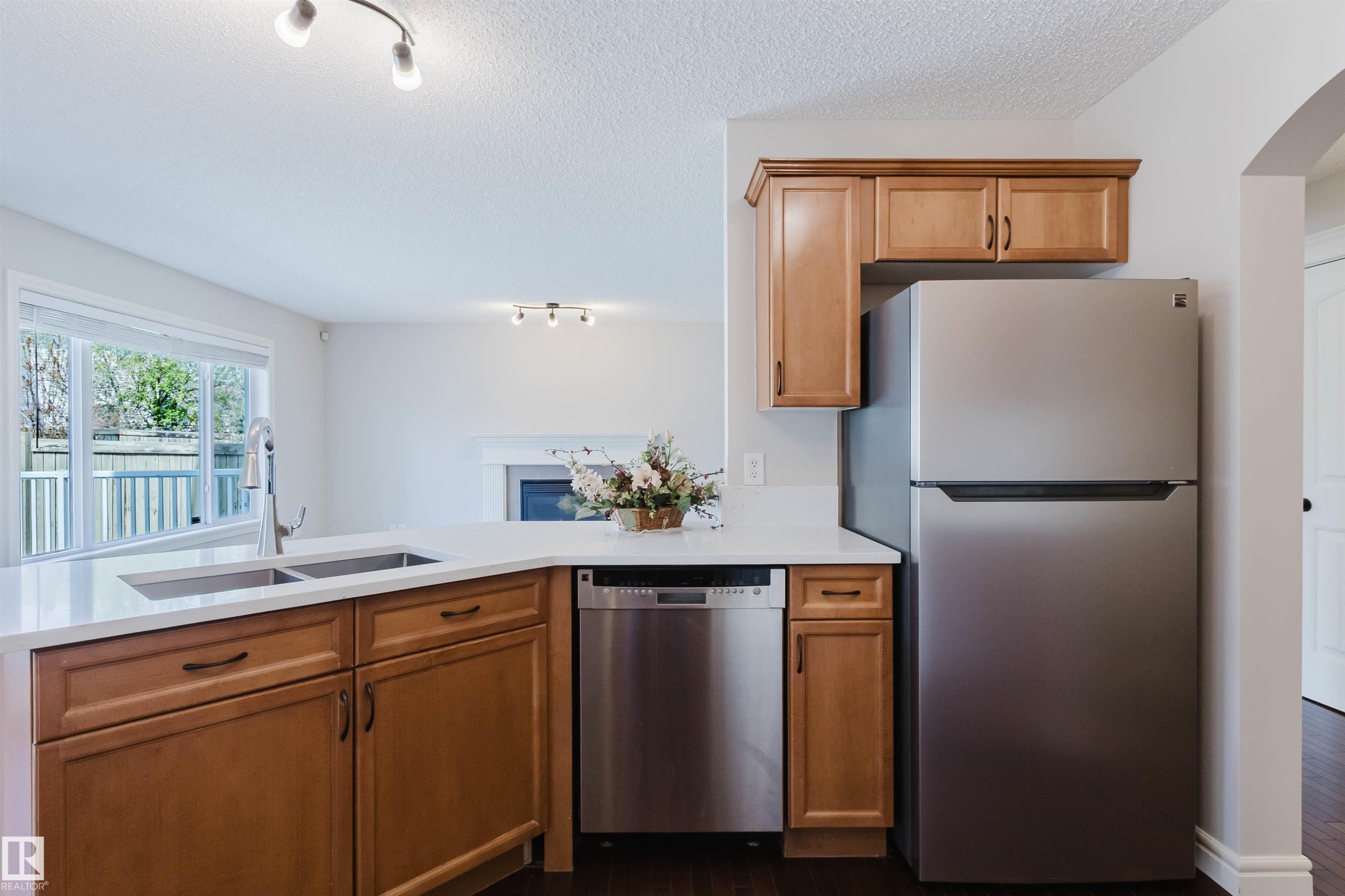 Kitchen featuring wood-finish cabinetry, stainless steel appliances, a double basin sink, and white countertops - 1140 115 Street, Edmonton, AB - Indoor Photo Showing Kitchen With Double Sink