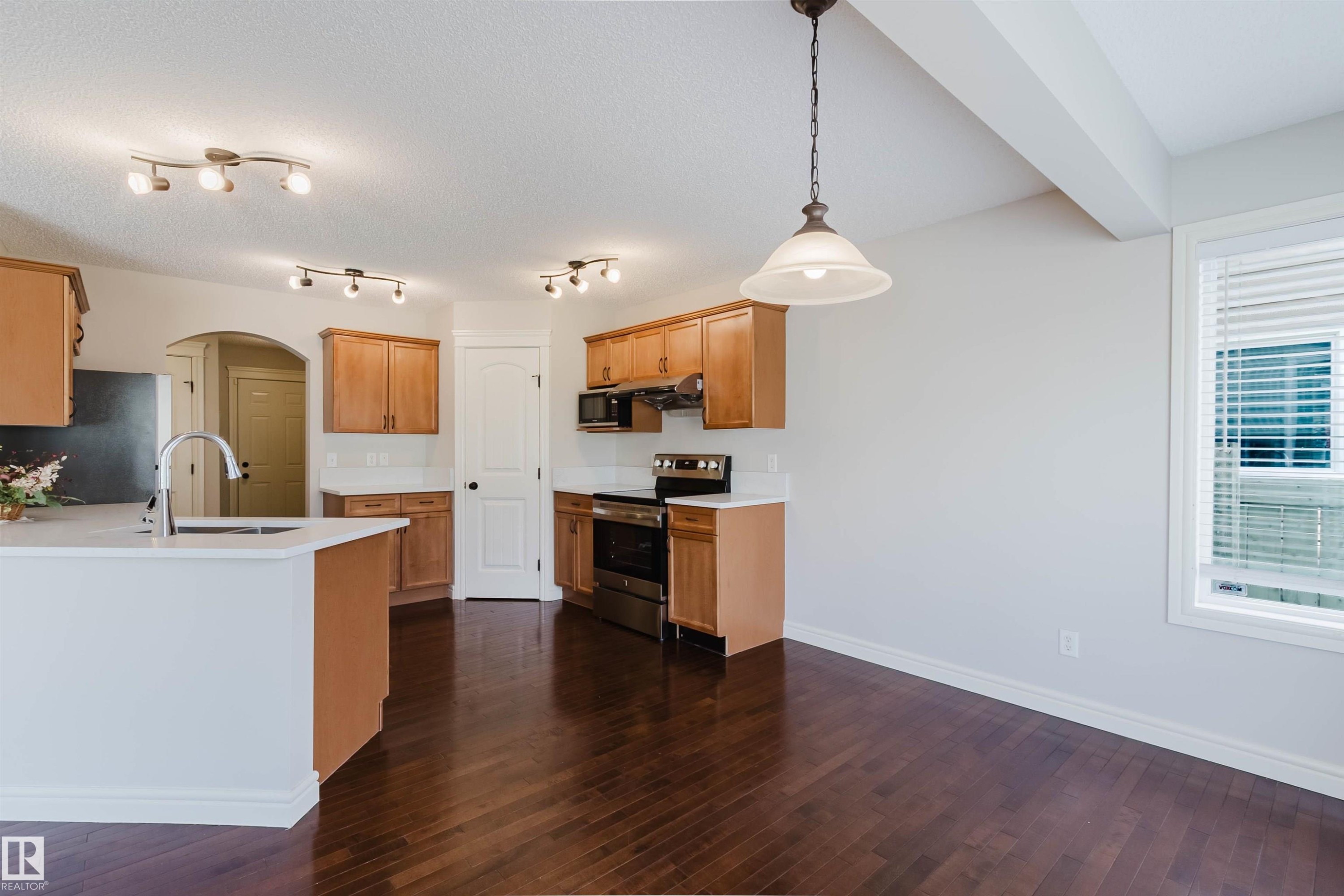 Open-concept kitchen and dining area featuring rich wood-finish flooring, light wood cabinetry, and white countertops - 1140 115 Street, Edmonton, AB - Indoor Photo Showing Kitchen