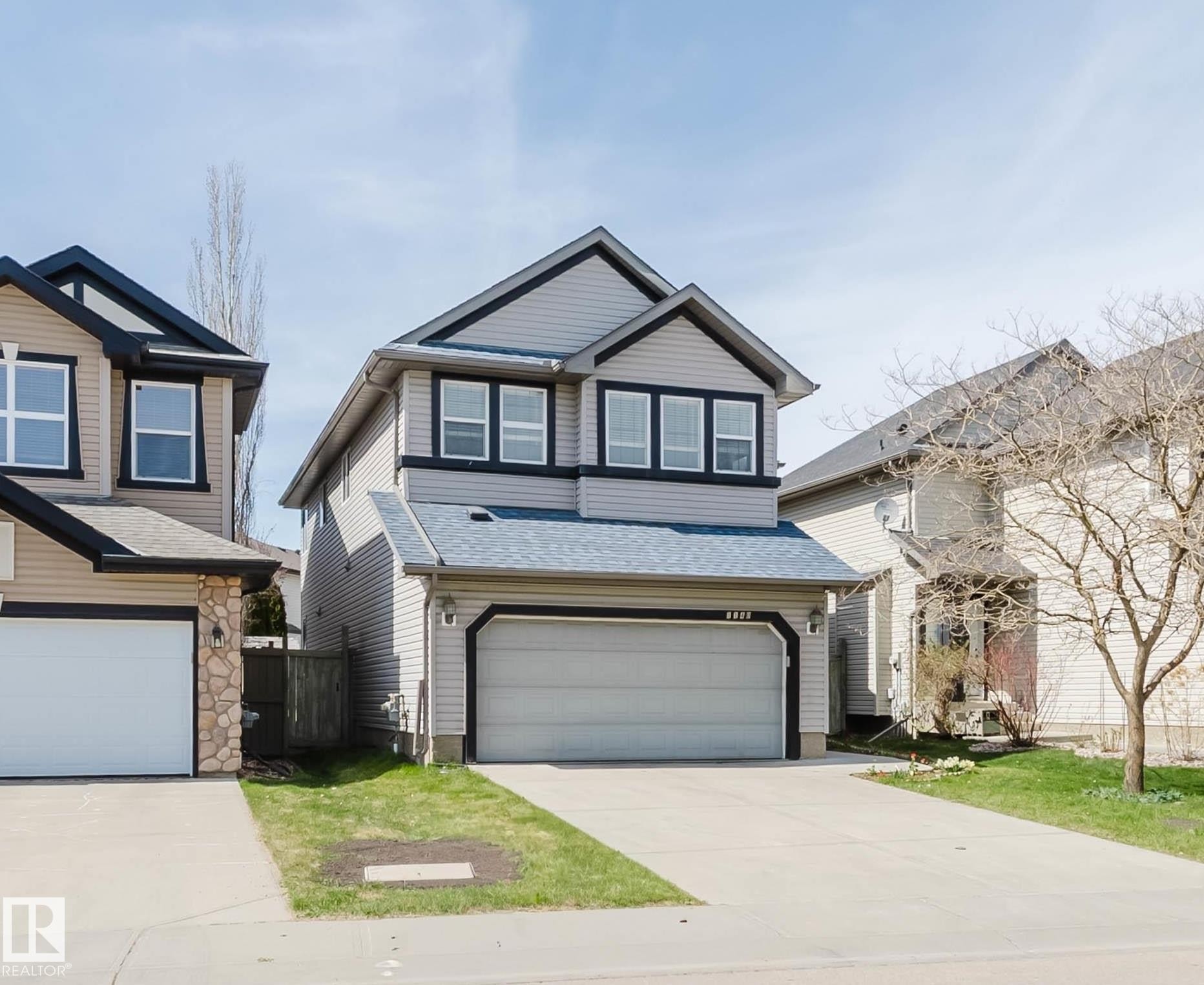 Two-story residence featuring a two-car garage, stone accents, tan siding, and dark trim - 1140 115 Street, Edmonton, AB - Outdoor With Facade