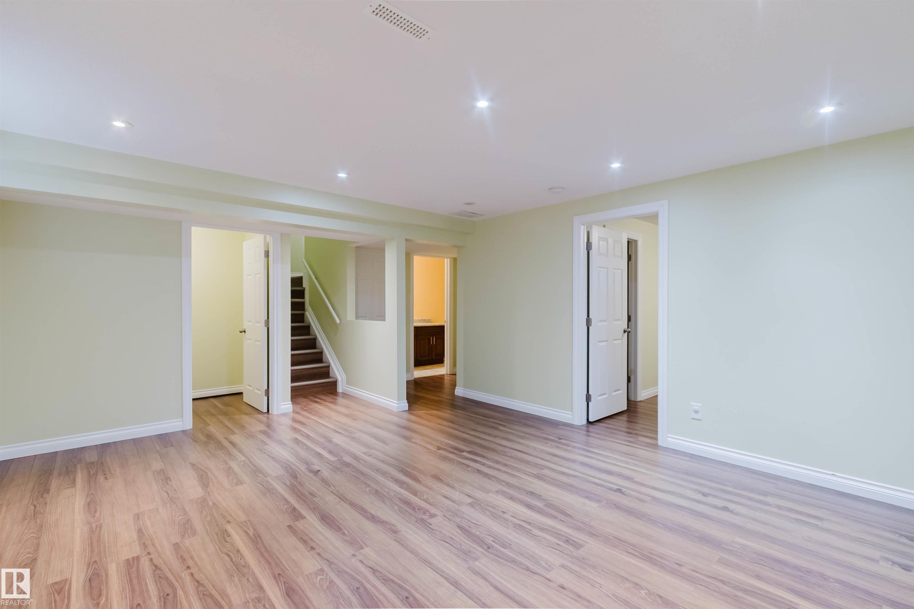 Spacious interior featuring wood-finish flooring, recessed ceiling lighting, light-toned walls, white trim, and multiple doorways - 1140 115 Street, Edmonton, AB - Indoor Photo Showing Other Room