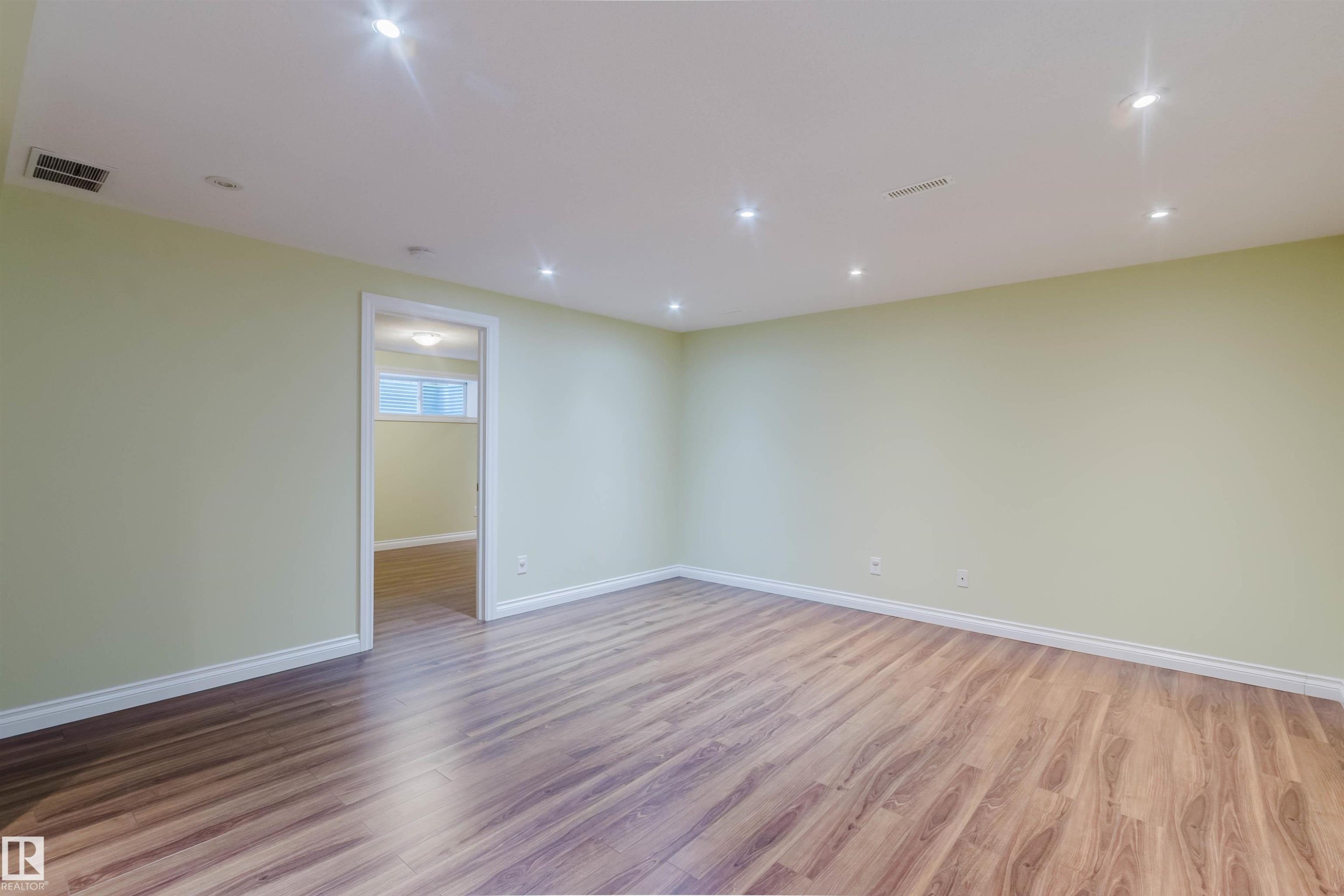 Spacious room with wood-finish flooring, recessed ceiling lighting, and light green painted walls with white baseboards - 1140 115 Street, Edmonton, AB - Indoor Photo Showing Other Room