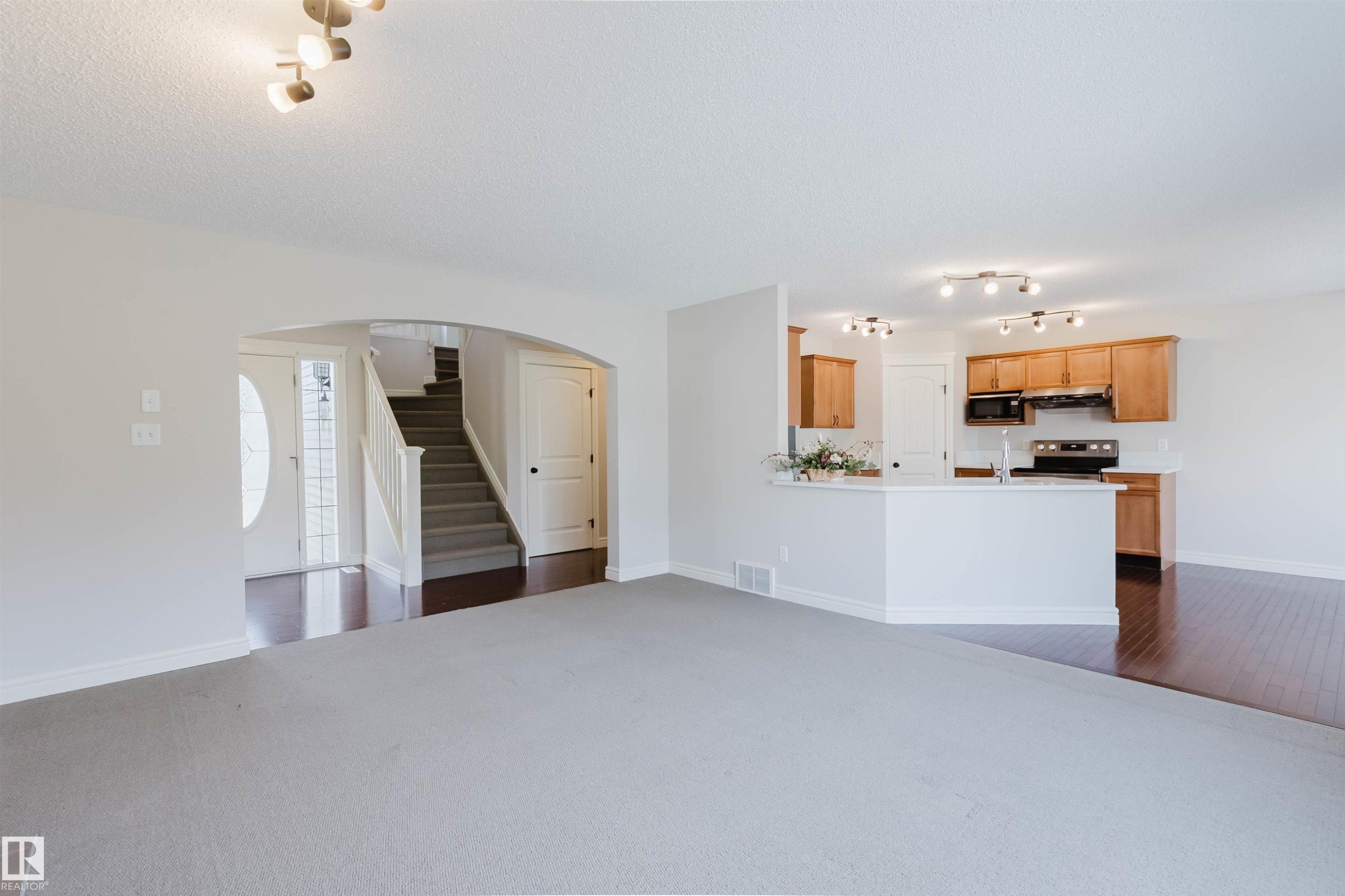 Open-concept living area featuring light gray carpeting and an arched entryway - 1140 115 Street, Edmonton, AB - Indoor Photo Showing Kitchen