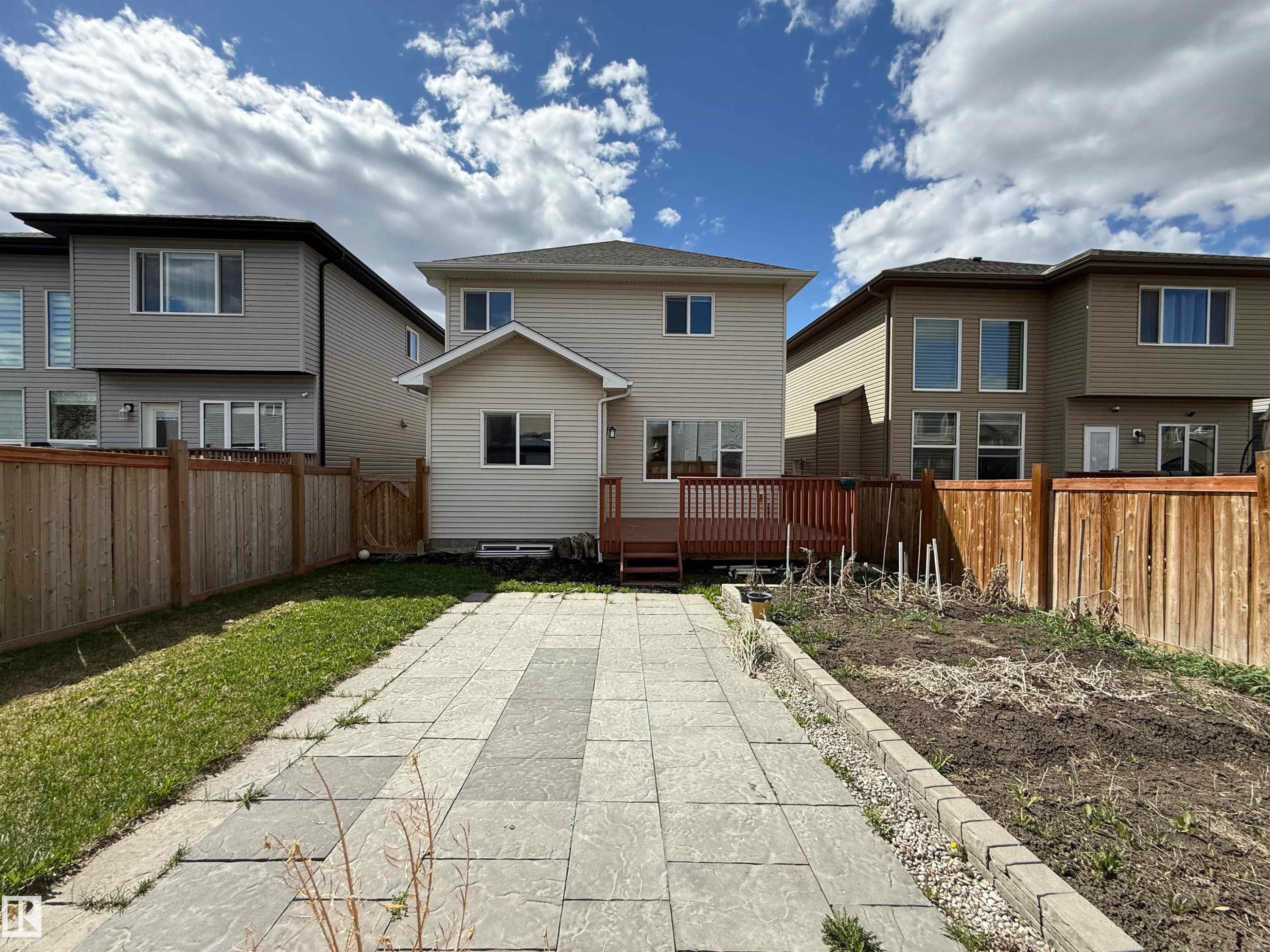 Expansive backyard featuring a concrete paver patio, a raised garden bed, and a wooden privacy fence - 4875 Wright Drive, Edmonton, AB - Outdoor