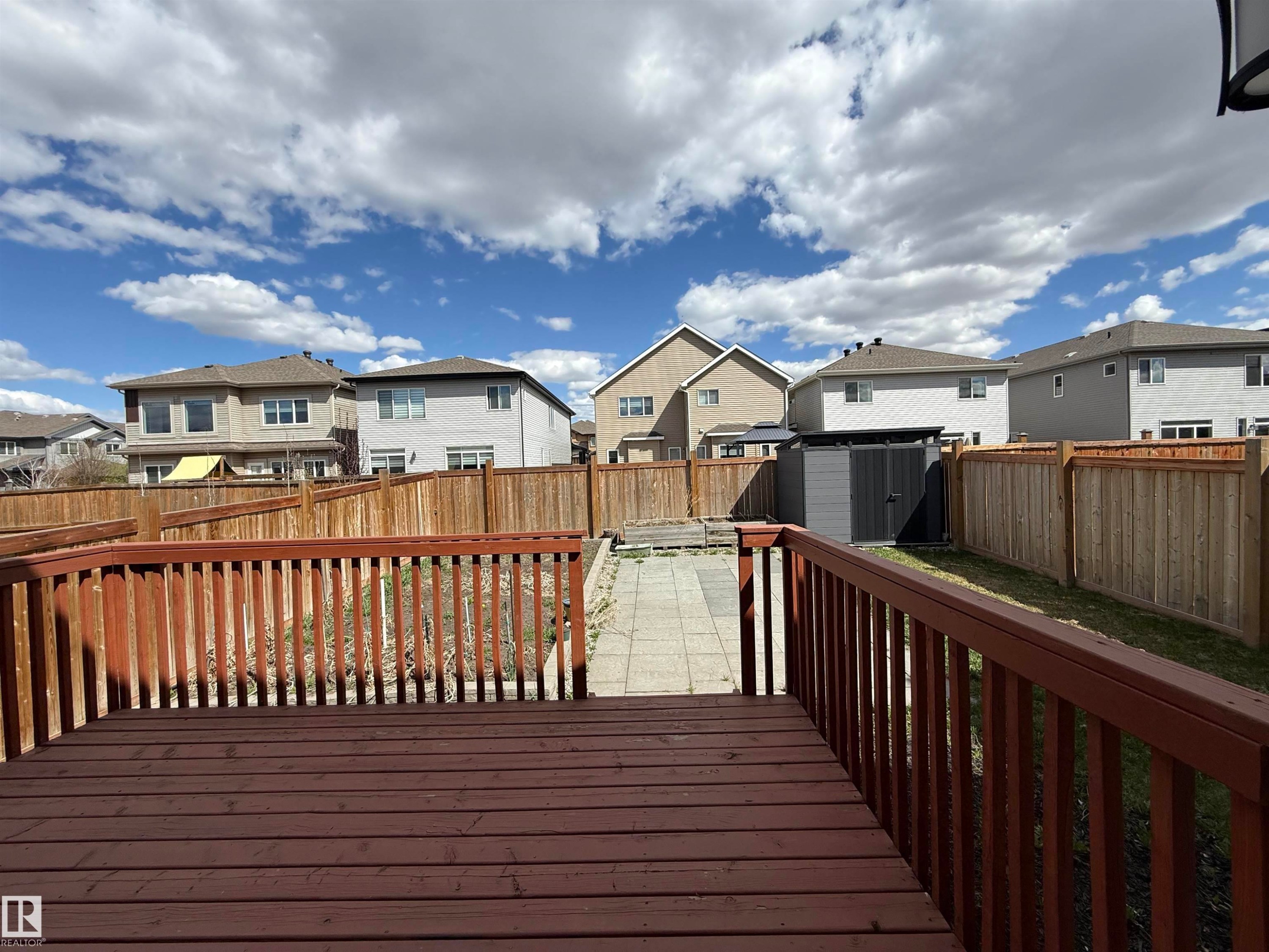 Expansive backyard featuring a stained wood deck, full privacy fencing, a paver stone walkway, and a modern storage shed - 4875 Wright Drive, Edmonton, AB - Outdoor With Deck Patio Veranda With Exterior
