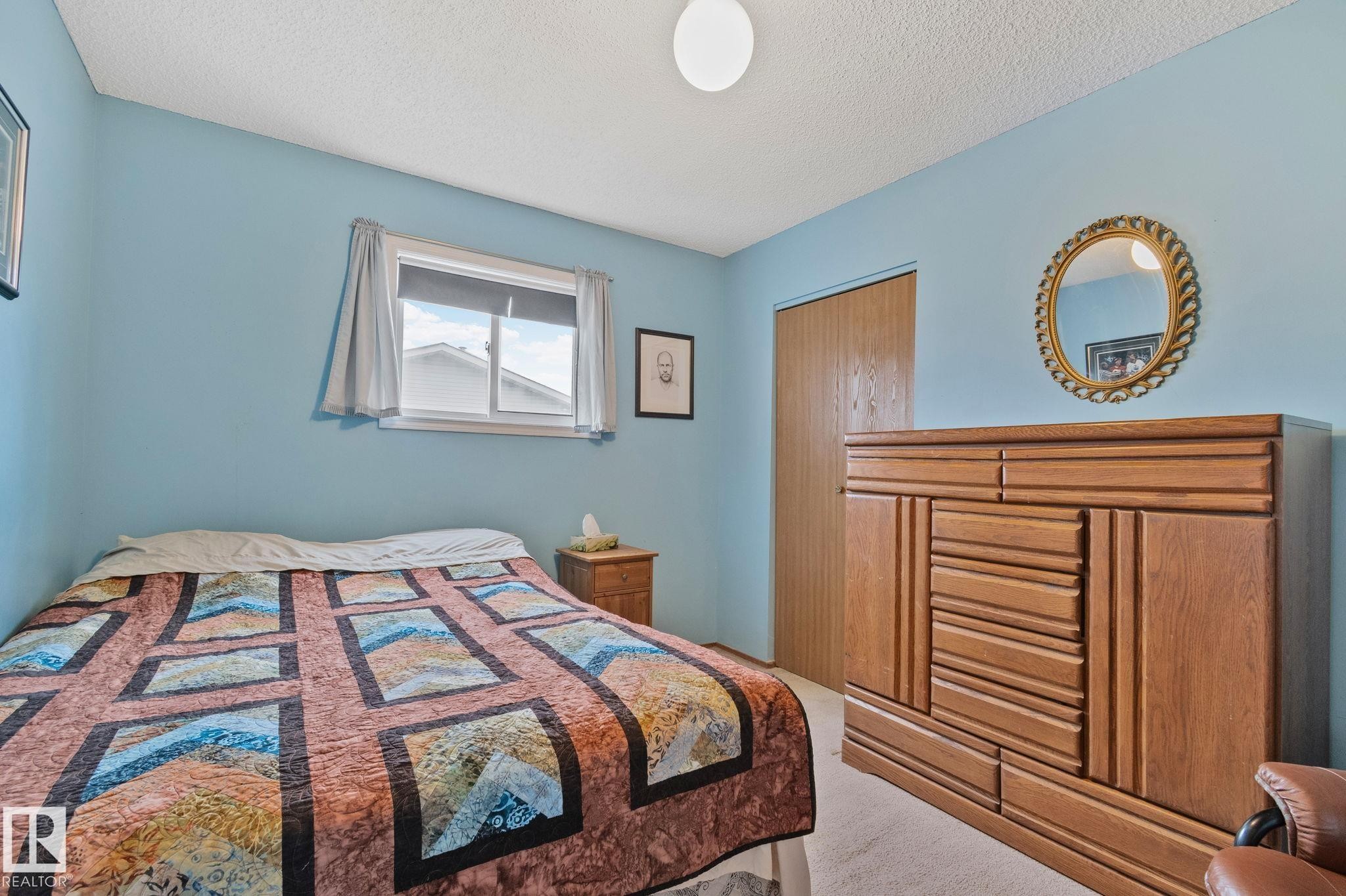 Carpeted bedroom with a single window, overhead flush mount lighting, and a wood-finish closet door - 4707 10A Avenue, Edmonton, AB - Indoor Photo Showing Bedroom