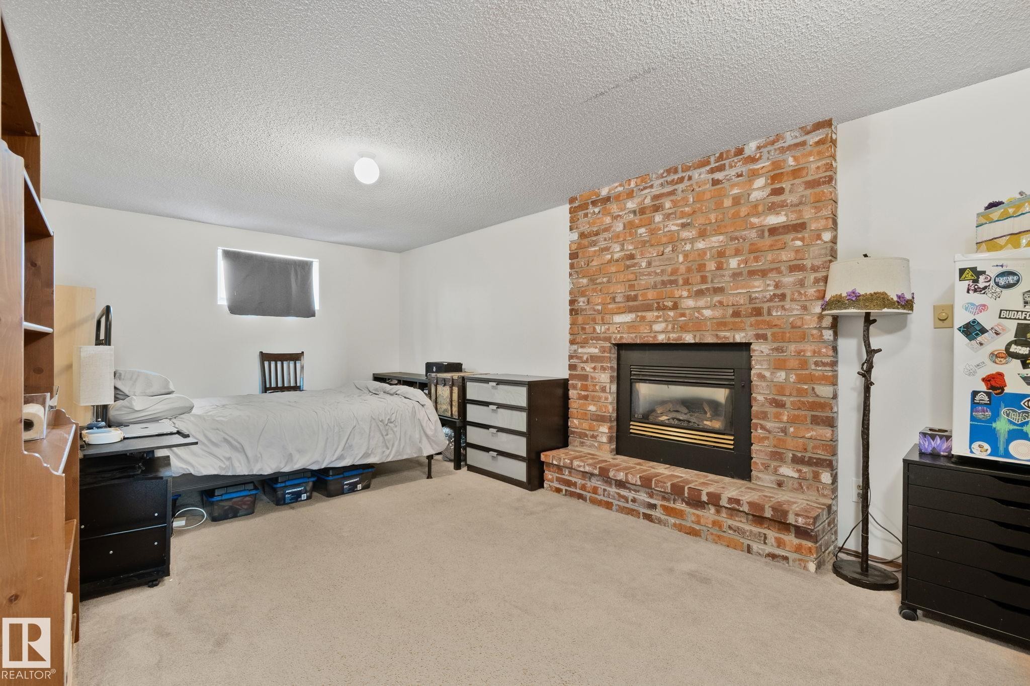 Brick-front fireplace with a black insert and a raised hearth - 4707 10A Avenue, Edmonton, AB - Indoor Photo Showing Bedroom With Fireplace