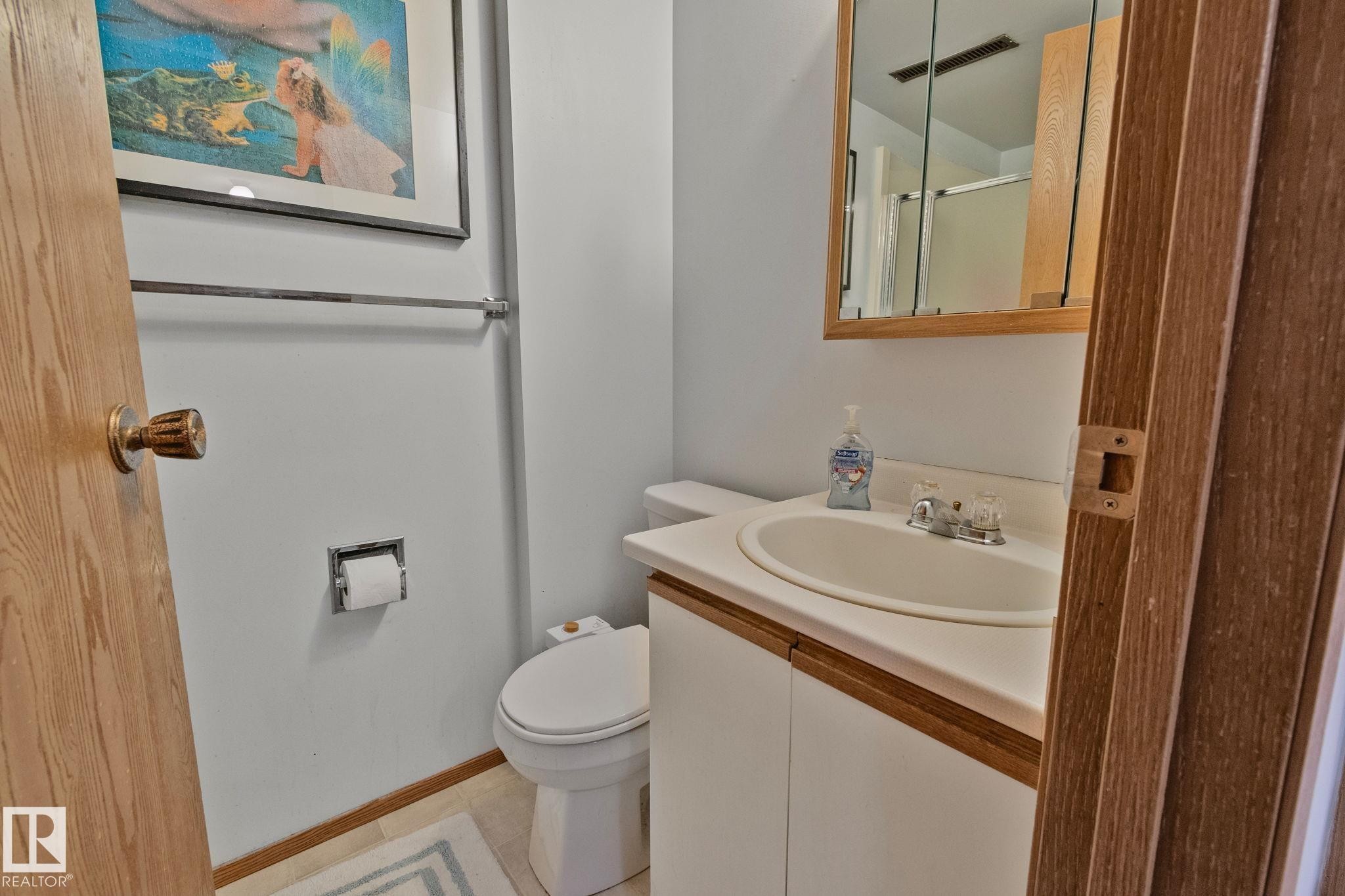 Bathroom featuring a vanity with an integrated sink, laminate countertop, and wood-finish cabinetry - 4707 10A Avenue, Edmonton, AB - Indoor Photo Showing Bathroom