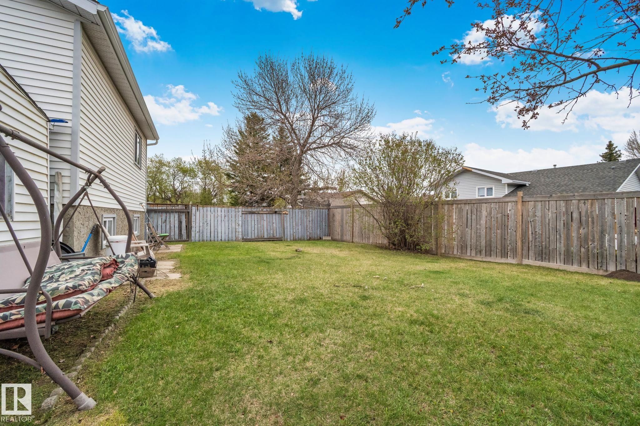 Expansive backyard featuring a manicured lawn, full perimeter wood fencing, and mature trees - 4707 10A Avenue, Edmonton, AB - Outdoor