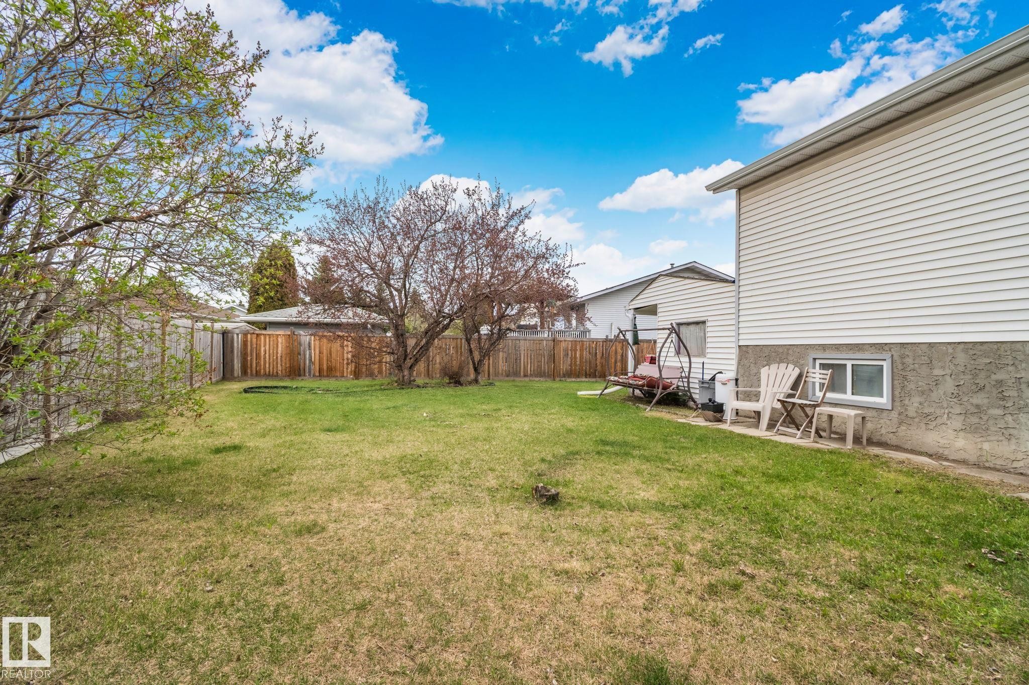 Expansive grassy yard with perimeter fencing, mature trees, and a siding exterior - 4707 10A Avenue, Edmonton, AB - Outdoor