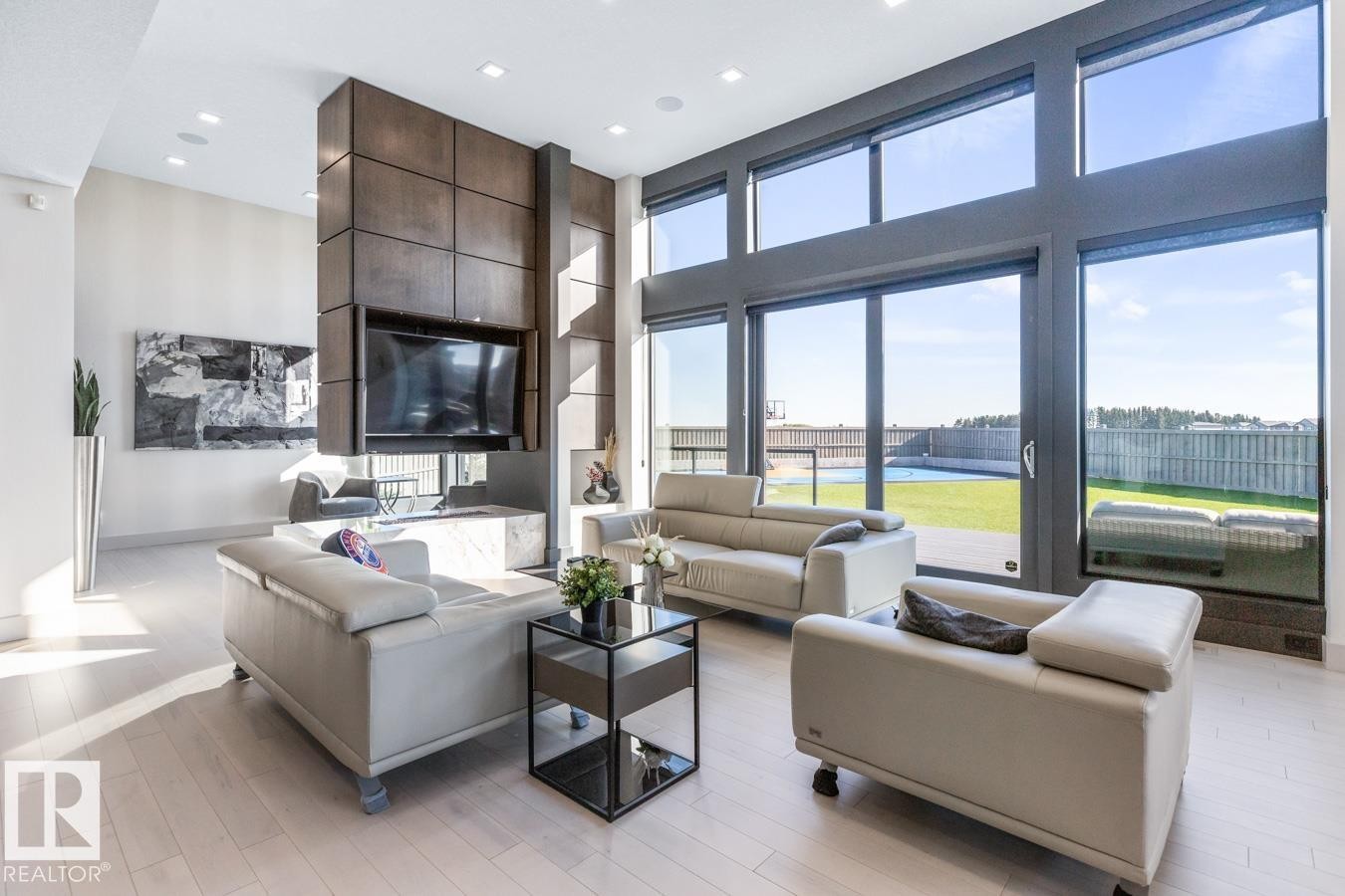 Main Floor Living Space featuring Floor to Ceiling Windows with Motorized Hunter Douglas Blinds, Opti-Myst Fireplace, and Custom Entertainment Unit. - 5536 Chegwin Point(E), Edmonton, AB - Indoor Photo Showing Living Room
