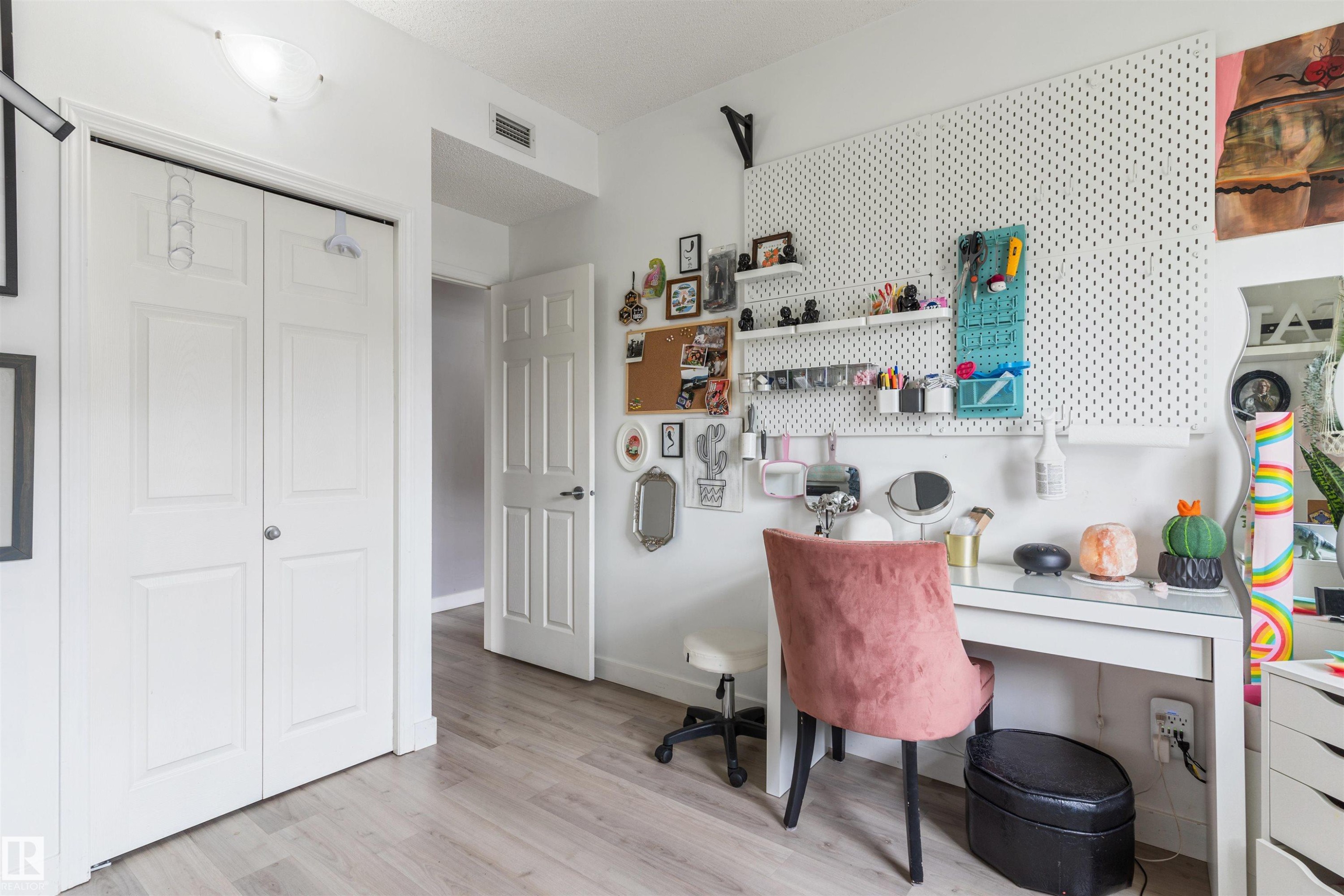 Light-toned wood-finish flooring provides a neutral base for this room featuring white bi-fold closet doors and a white paneled interior door - 73 3040 Spence Wynd, Edmonton, AB - Indoor