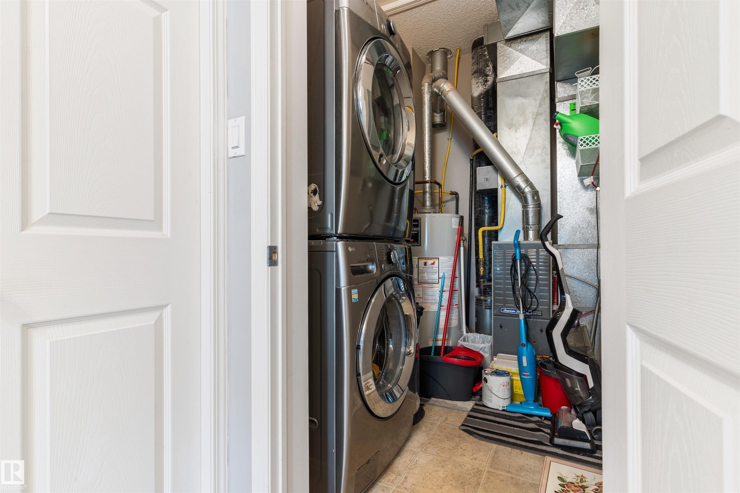 Utility area featuring a stacked washer and dryer, water heater, and furnace - 73 3040 Spence Wynd, Edmonton, AB - Indoor Photo Showing Laundry Room