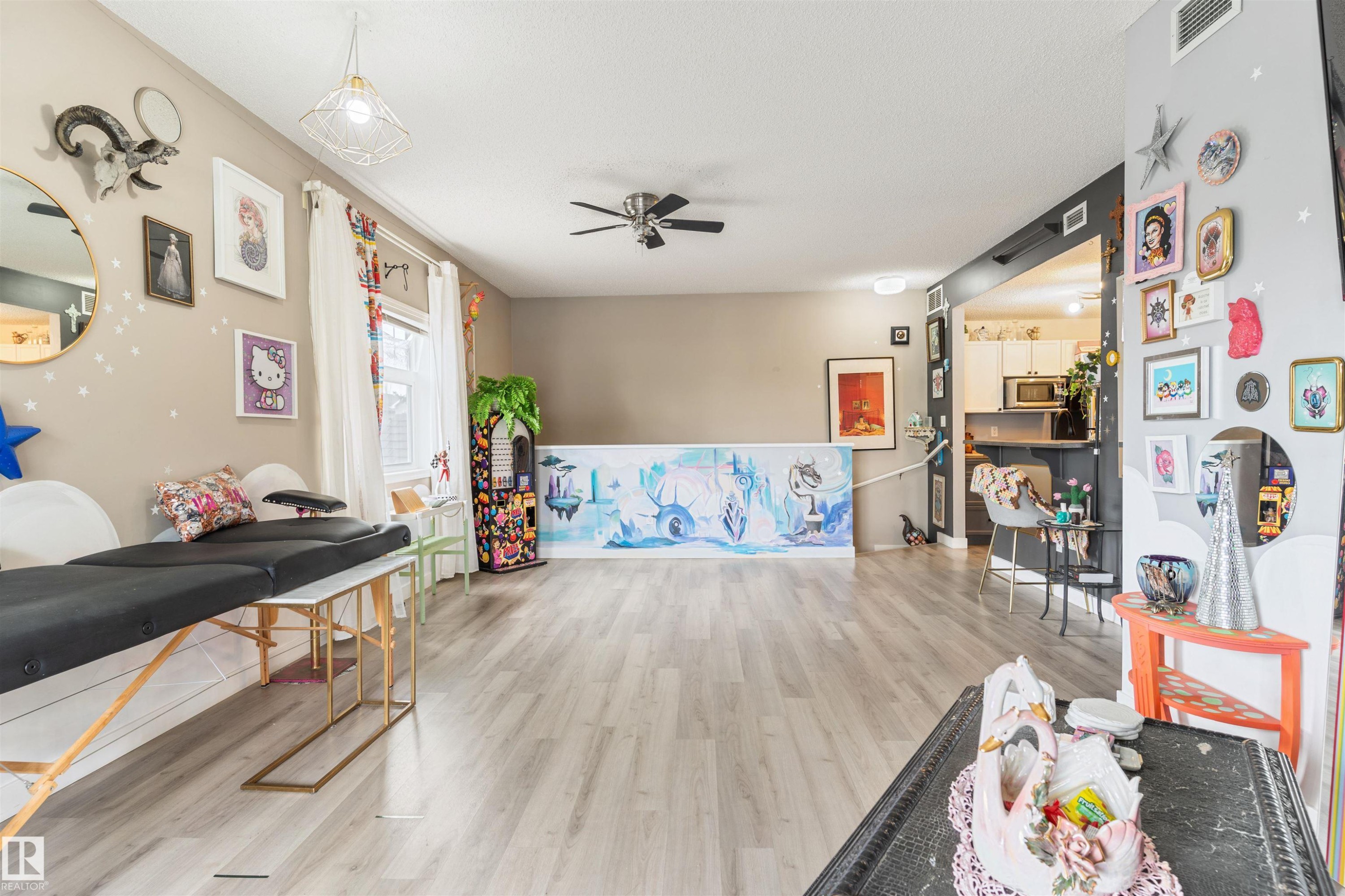 Spacious room featuring wood-finish flooring, neutral wall paint, and a ceiling fan with integrated lighting - 73 3040 Spence Wynd, Edmonton, AB - Indoor
