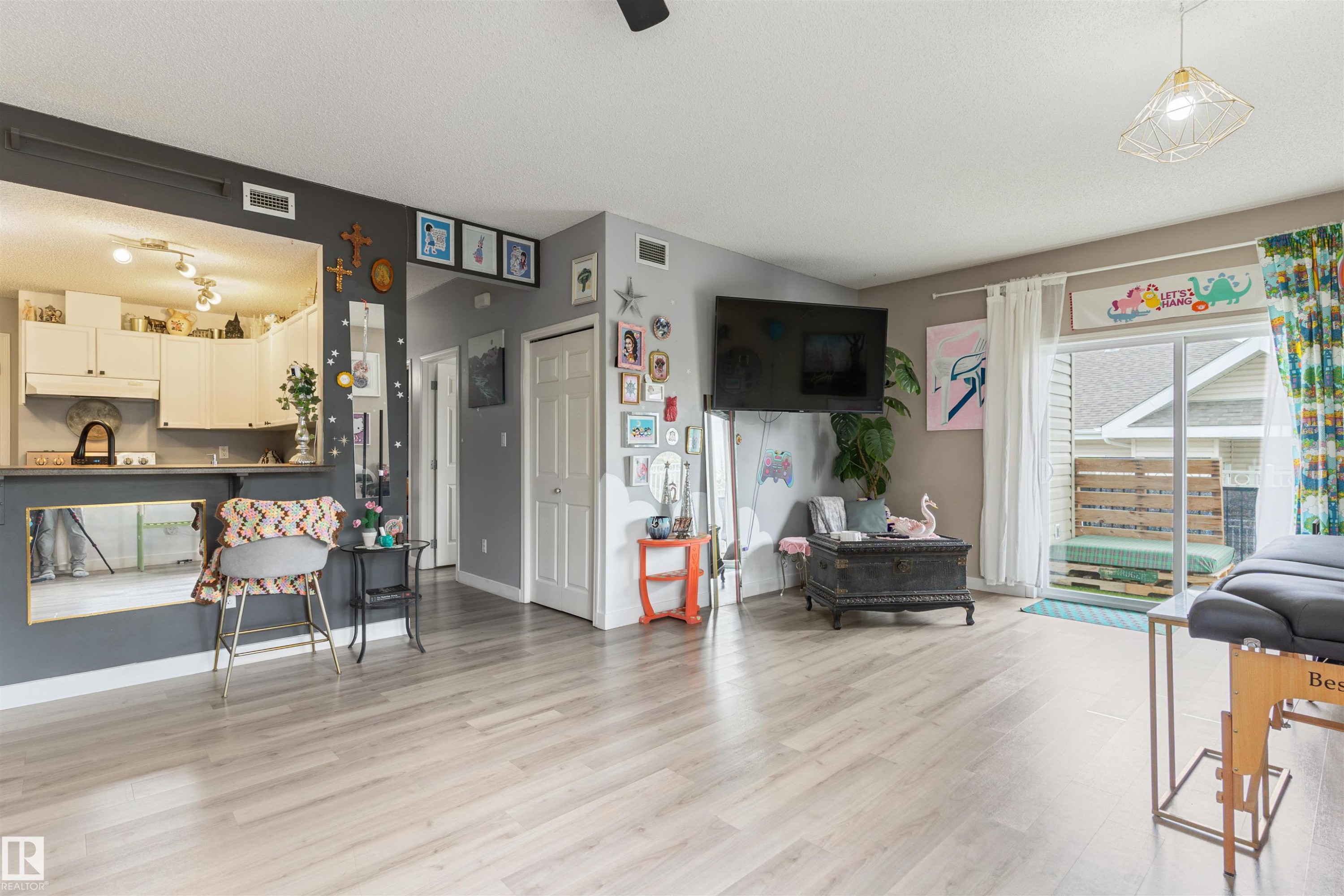 Open-concept living space featuring wood-finish flooring, a pass-through window to the kitchen, and a sliding glass door providing outdoor access - 73 3040 Spence Wynd, Edmonton, AB - Indoor Photo Showing Other Room