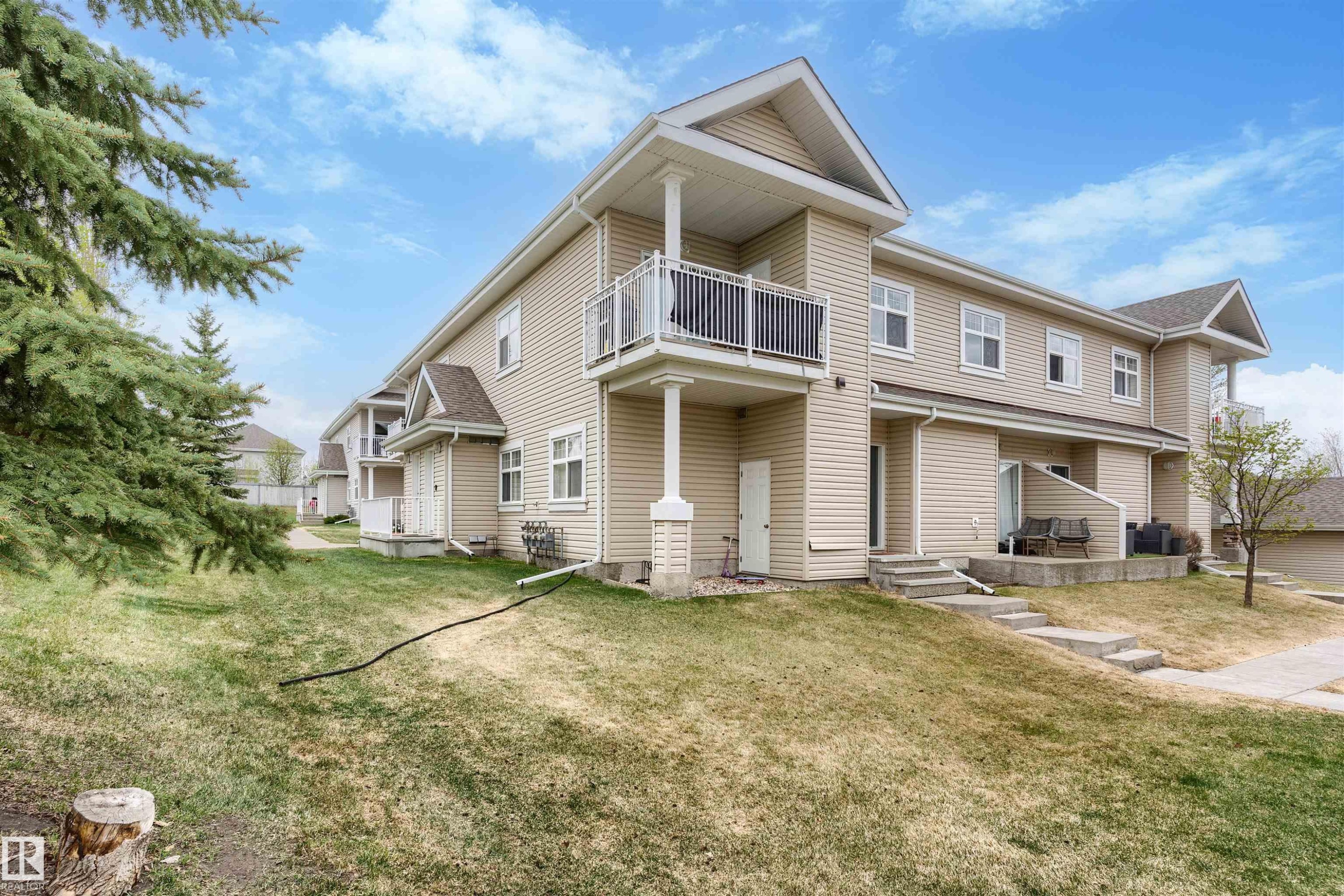 Tan siding exterior featuring multiple windows and a second-story balcony with white railing - 73 3040 Spence Wynd, Edmonton, AB - Outdoor