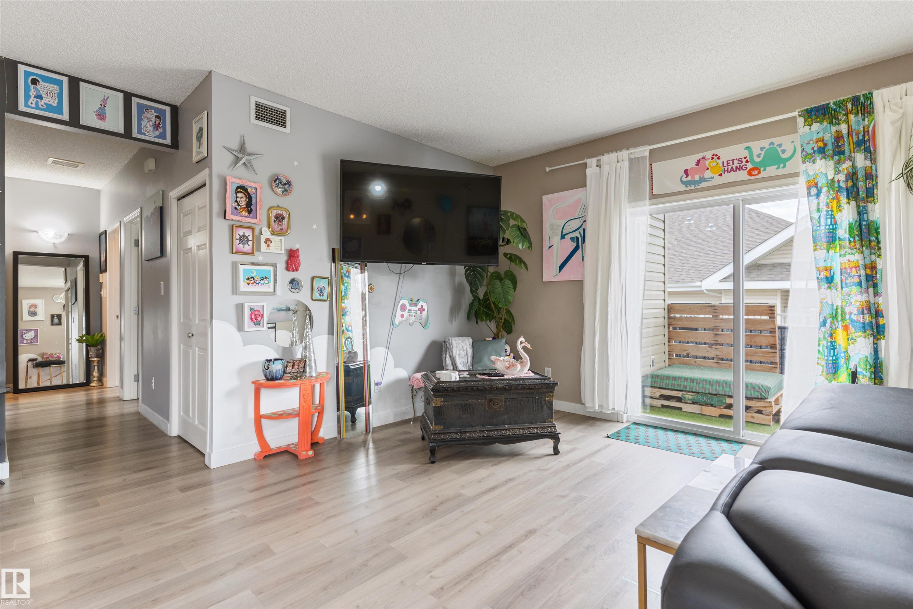 Open-concept living space featuring wood-finish flooring, a sliding glass door, and recessed lighting - 73 3040 Spence Wynd, Edmonton, AB - Indoor Photo Showing Living Room