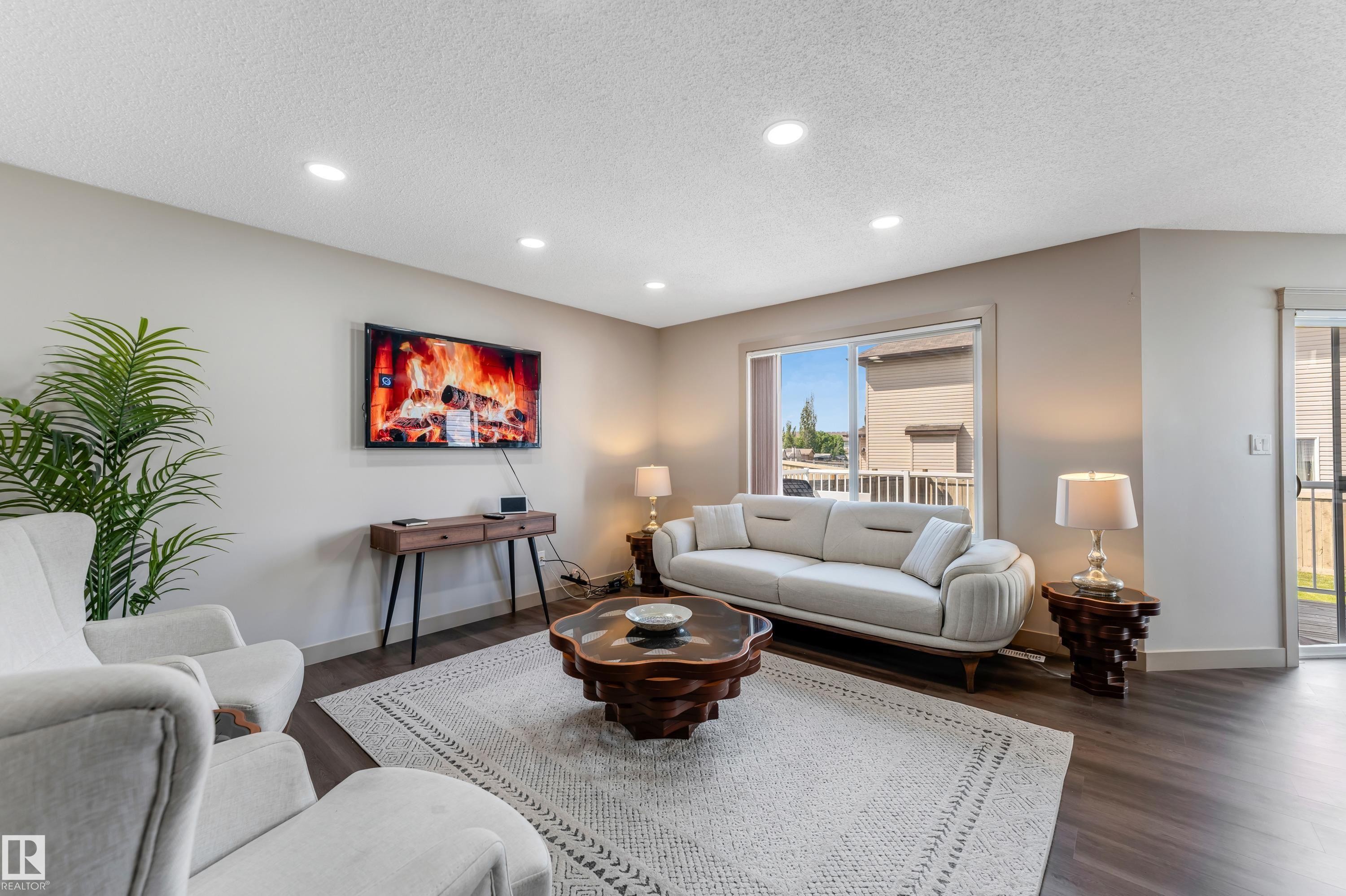 Living area featuring recessed lighting, hardwood style flooring, and a large window providing natural light - 463 Tamarack Green, Edmonton, AB - Indoor Photo Showing Living Room