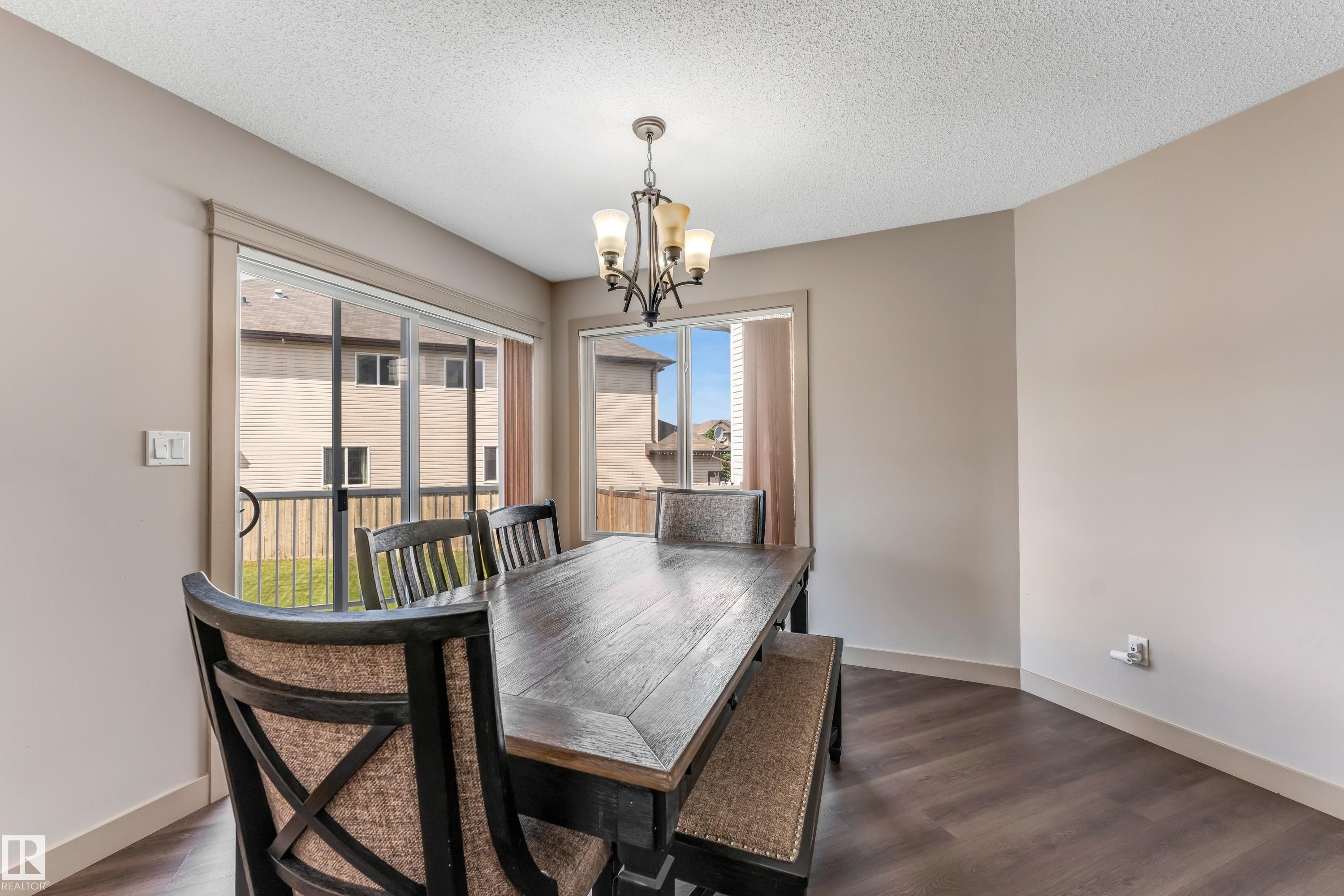 The property features a dining area with dark wood flooring and light-colored walls - 463 Tamarack Green, Edmonton, AB - Indoor Photo Showing Dining Room