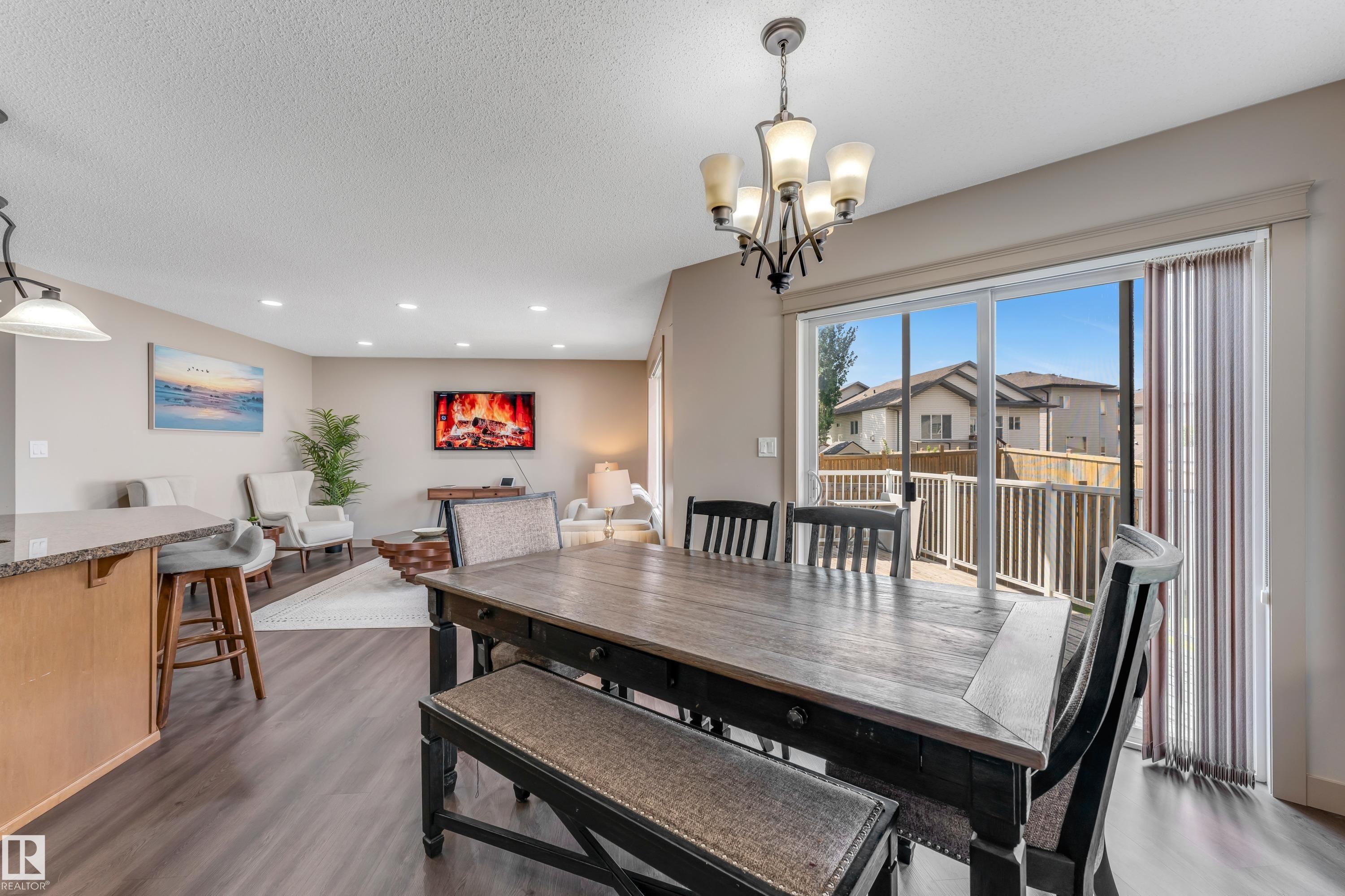 The property features an open living and dining area with dark wood flooring - 463 Tamarack Green, Edmonton, AB - Indoor Photo Showing Dining Room