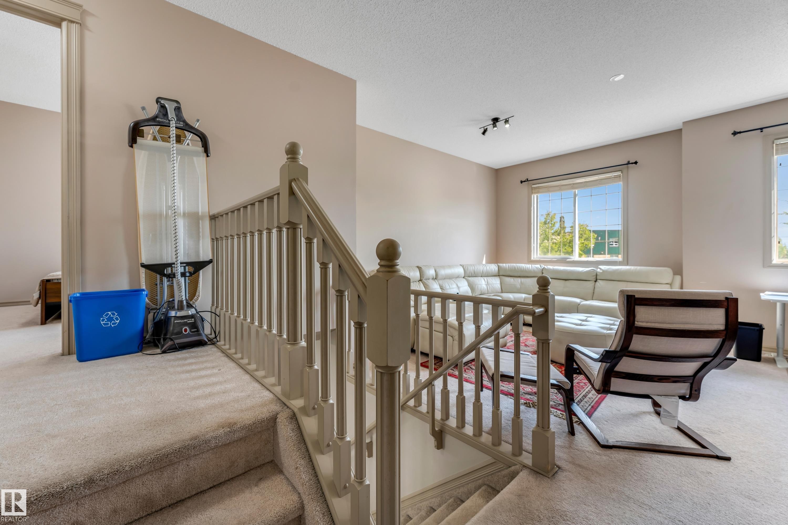 The property features carpeted floors, light-colored walls, and a staircase with a wooden railing - 463 Tamarack Green, Edmonton, AB - Indoor