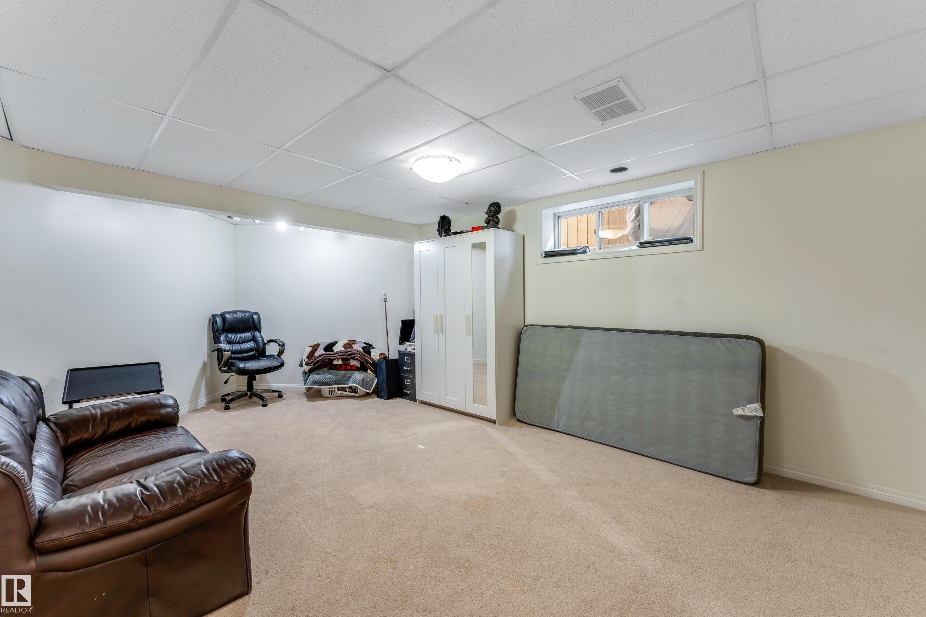 This versatile room features neutral carpeting, light-colored walls, recessed lighting, and a window - 463 Tamarack Green, Edmonton, AB - Indoor Photo Showing Basement