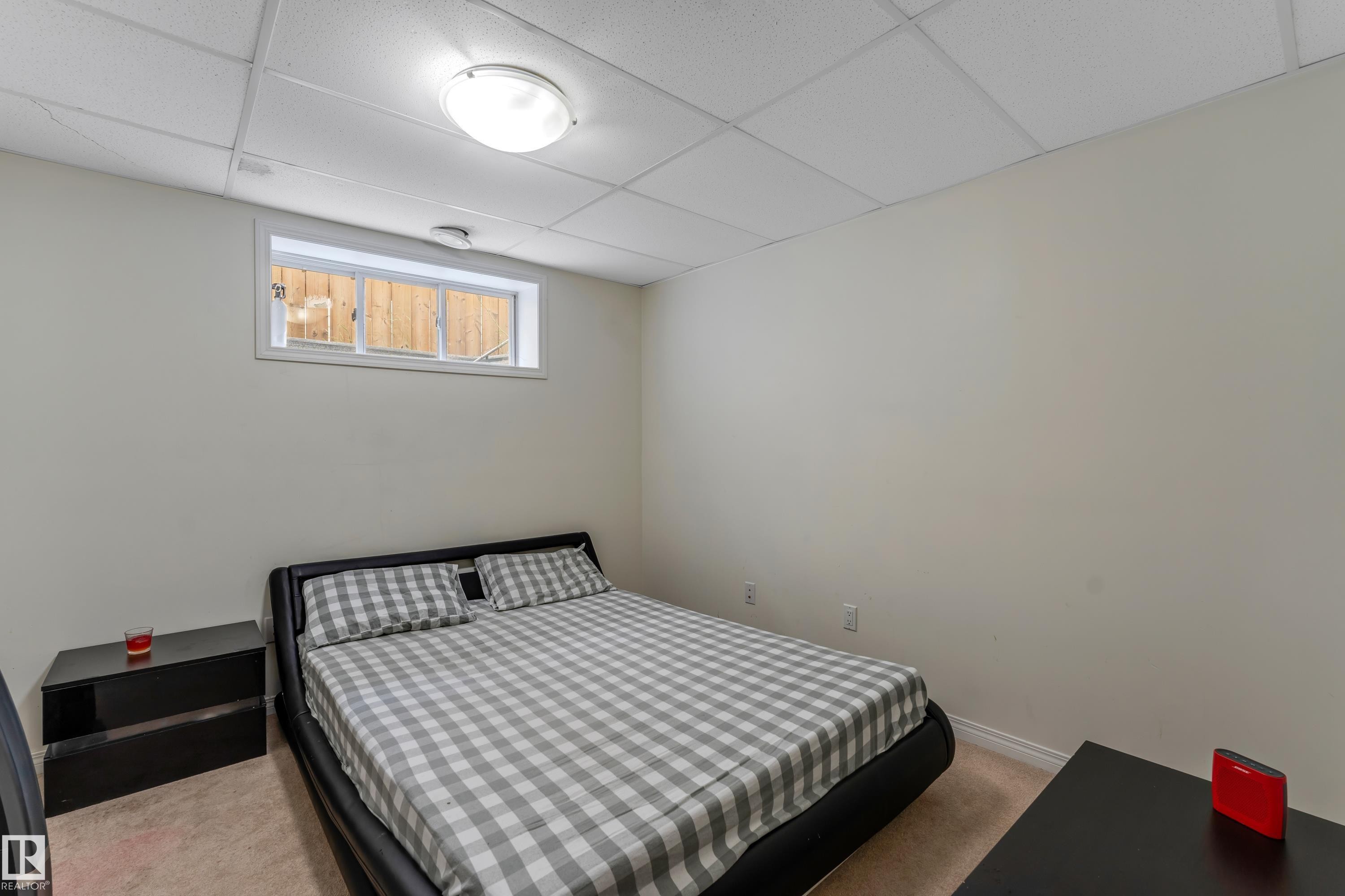 This room features neutral-toned walls, a drop ceiling with recessed lighting, and a window providing natural light - 463 Tamarack Green, Edmonton, AB - Indoor Photo Showing Bedroom