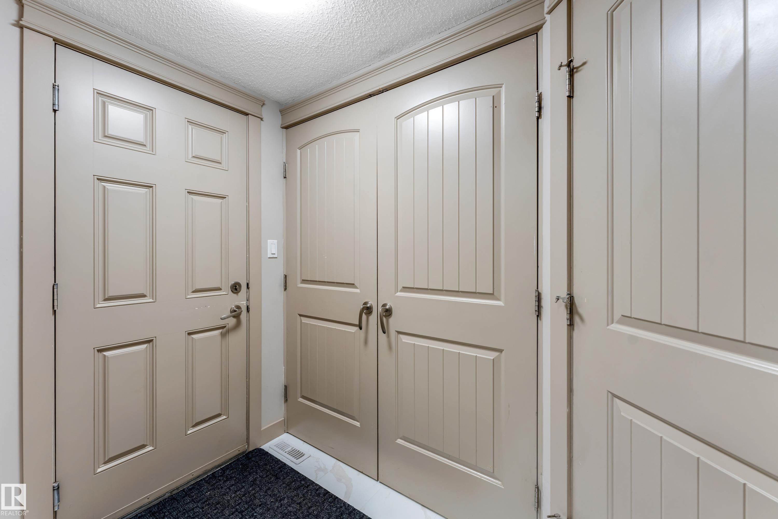 Entryway featuring a panel door, double bifold doors with vertical planking, and crown molding - 463 Tamarack Green, Edmonton, AB - Indoor Photo Showing Other Room