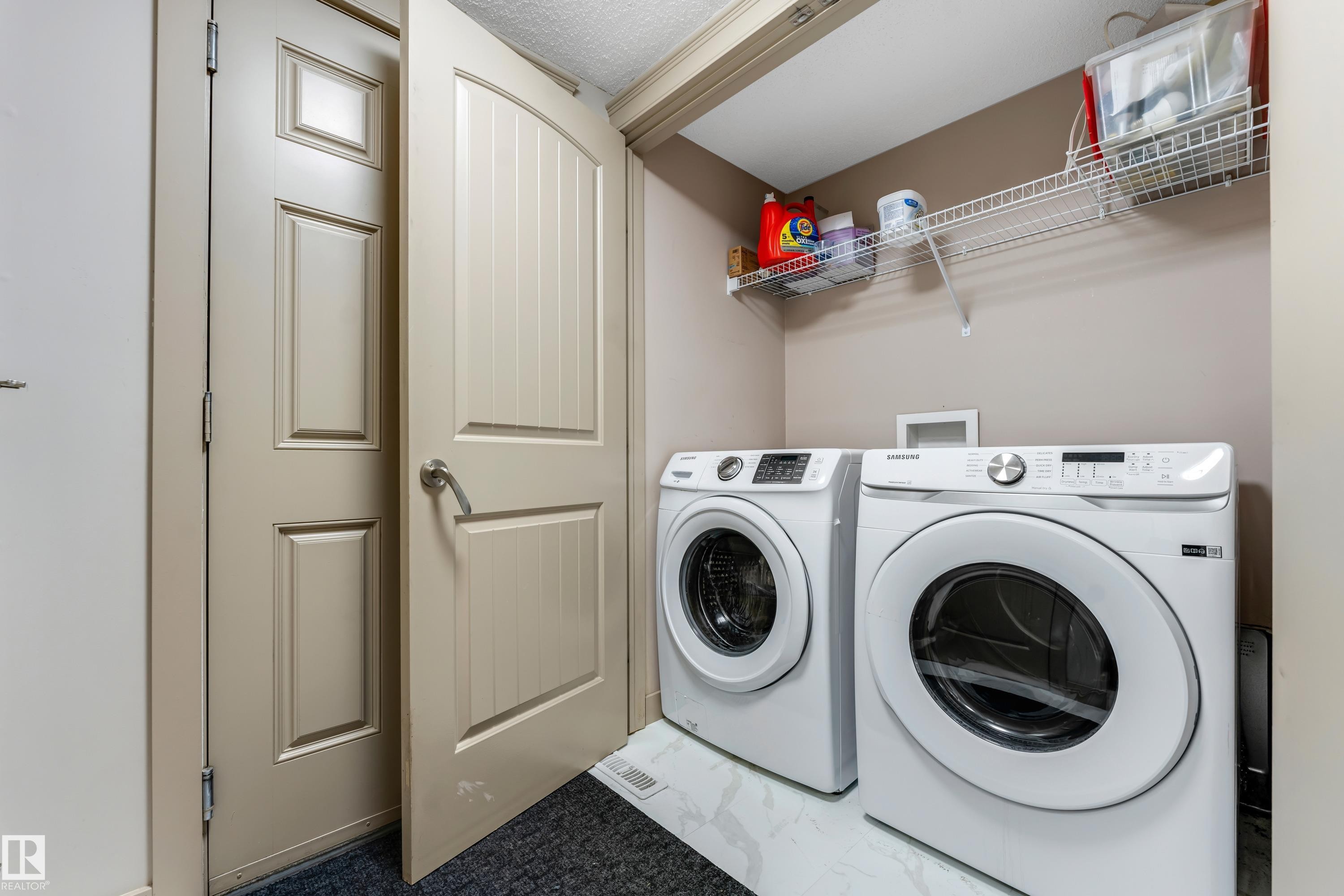 Dedicated laundry area featuring a white washing machine and dryer, a wire shelf for storage, and light-colored walls - 463 Tamarack Green, Edmonton, AB - Indoor Photo Showing Laundry Room