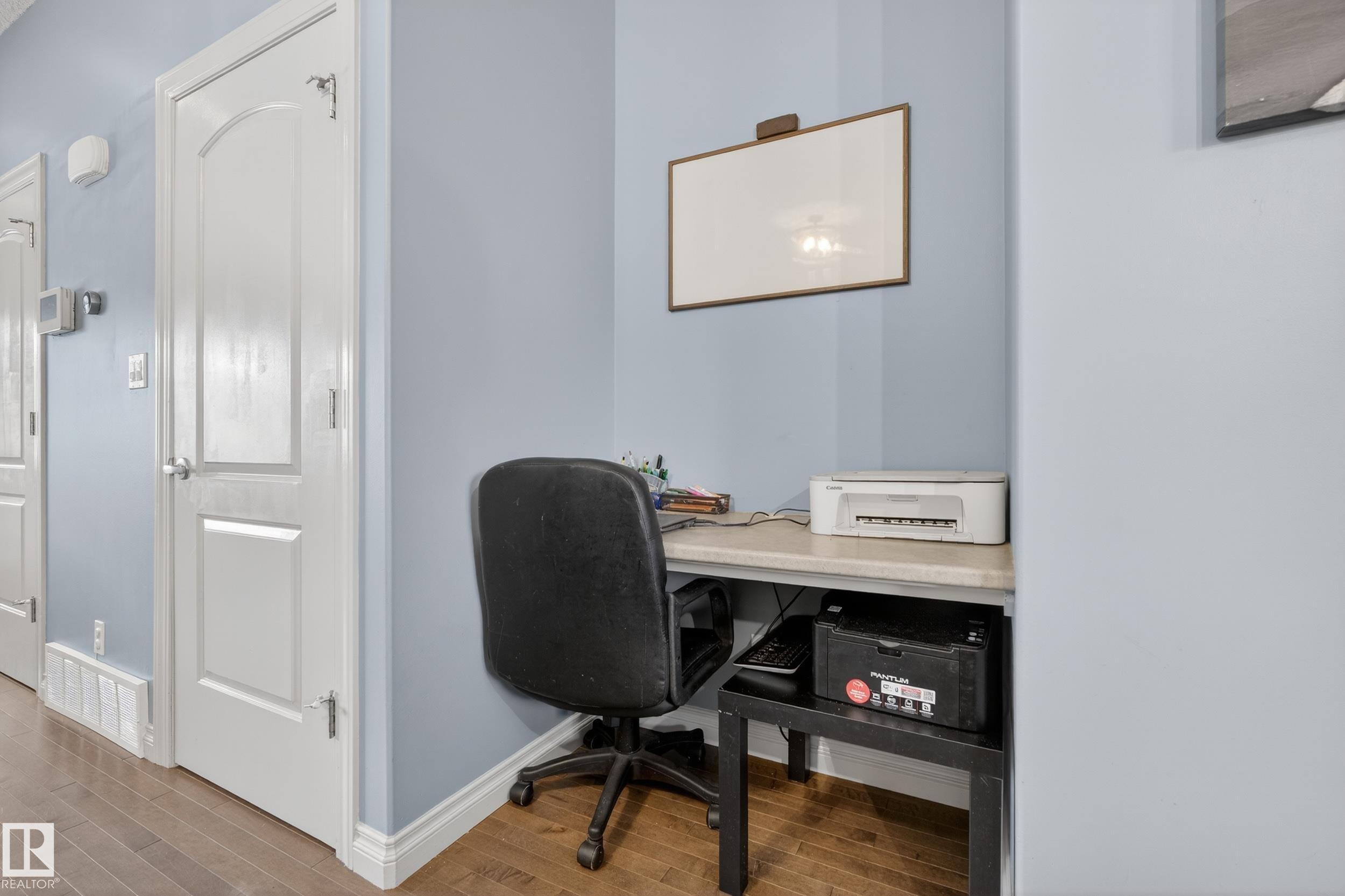 Built-in desk area with a light-toned countertop, wood-finish flooring, and white trim - 7074 Cardinal Way, Edmonton, AB - Indoor Photo Showing Office