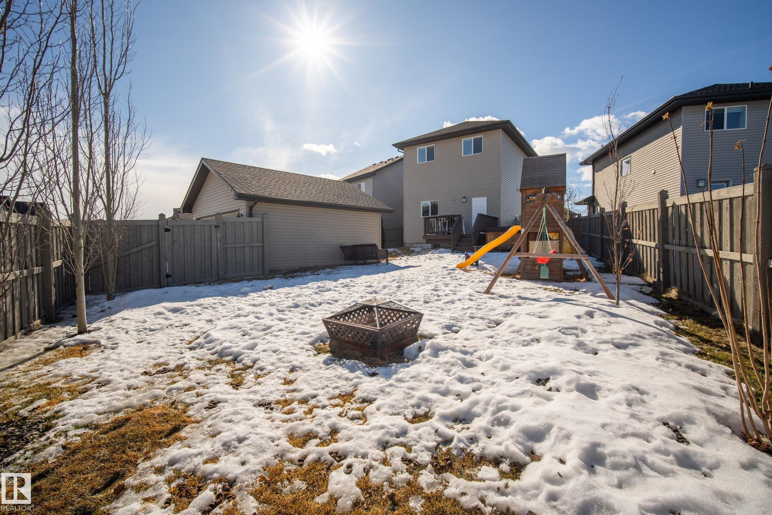 Spacious backyard featuring a fire pit, privacy fencing, and rear detached garage - 7074 Cardinal Way, Edmonton, AB - Outdoor