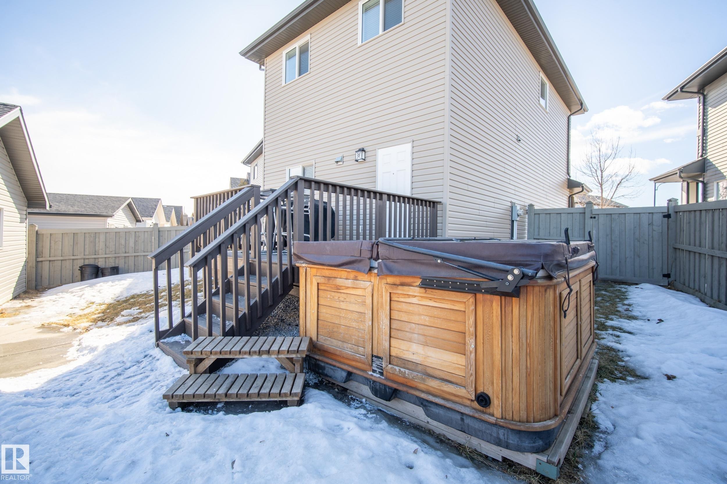 Fenced backyard featuring an exterior hot tub with a wood-finish surround, wood deck, and a privacy gate - 7074 Cardinal Way, Edmonton, AB - Outdoor With Deck Patio Veranda With Exterior