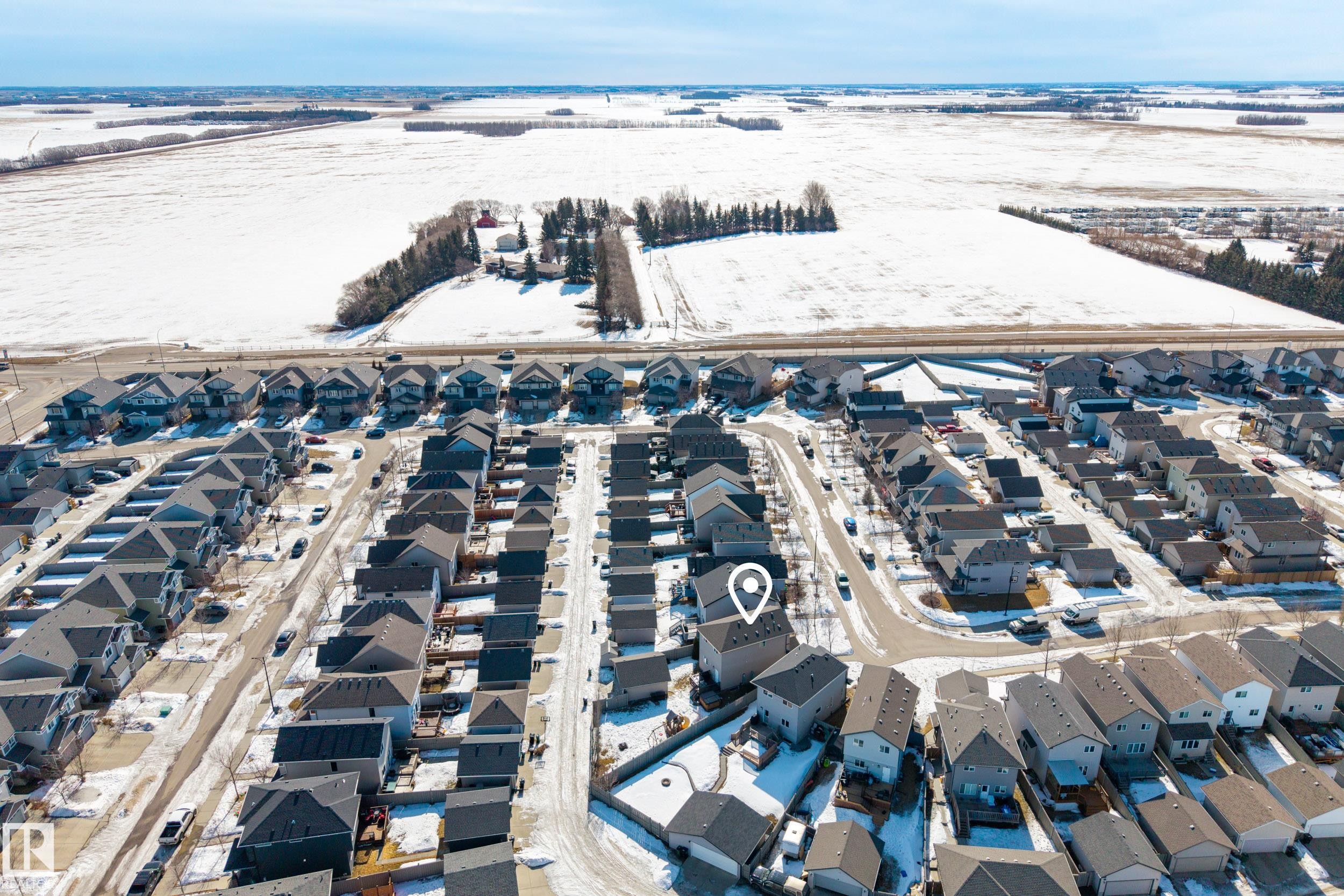 Residential neighborhood featuring an array of detached homes with dark shingle roofs, situated near agricultural fields - 7074 Cardinal Way, Edmonton, AB - Outdoor With View