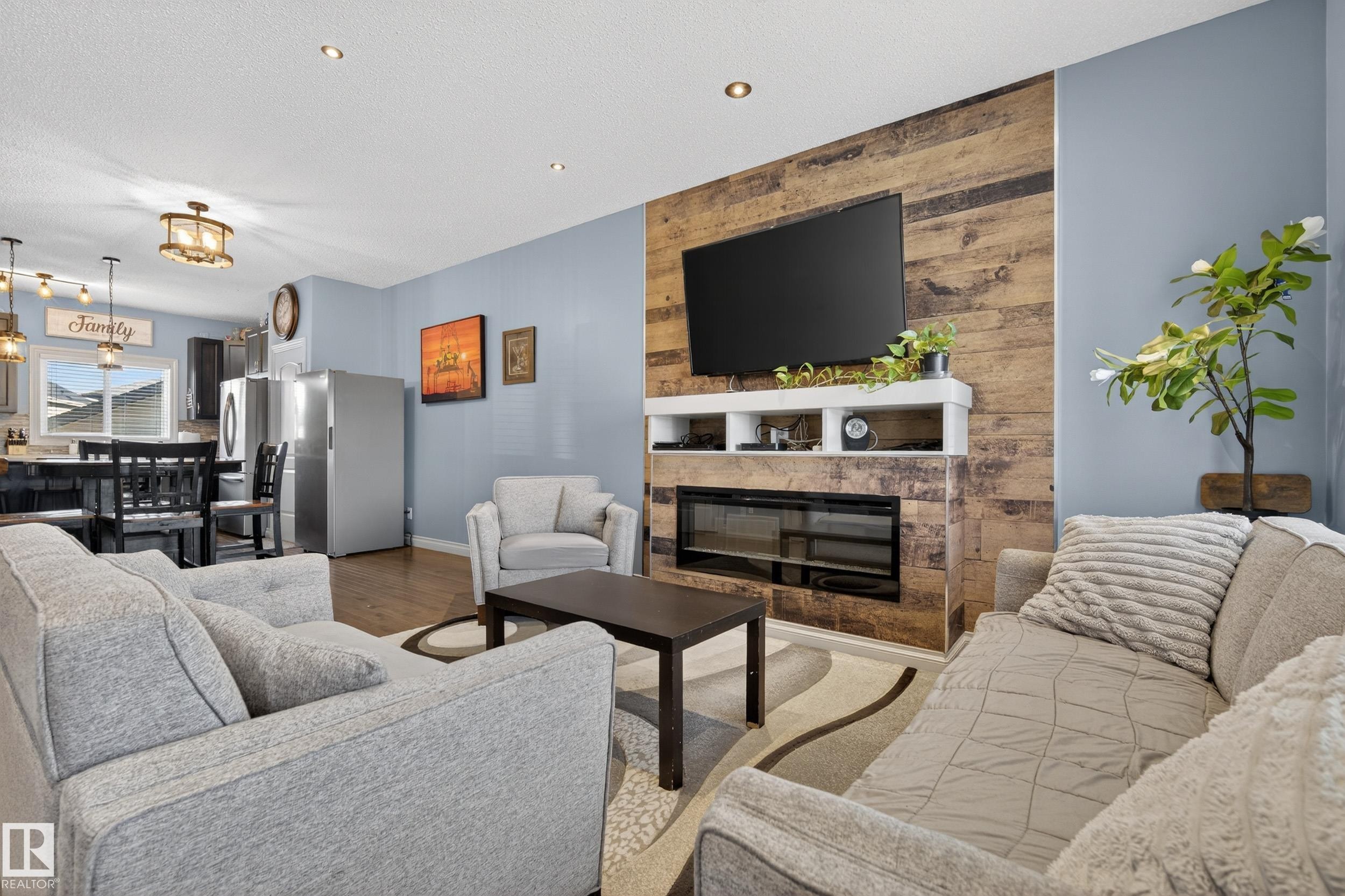 Contemporary living area featuring a rustic wood-plank accent wall and a built-in electric fireplace - 7074 Cardinal Way, Edmonton, AB - Indoor Photo Showing Living Room With Fireplace