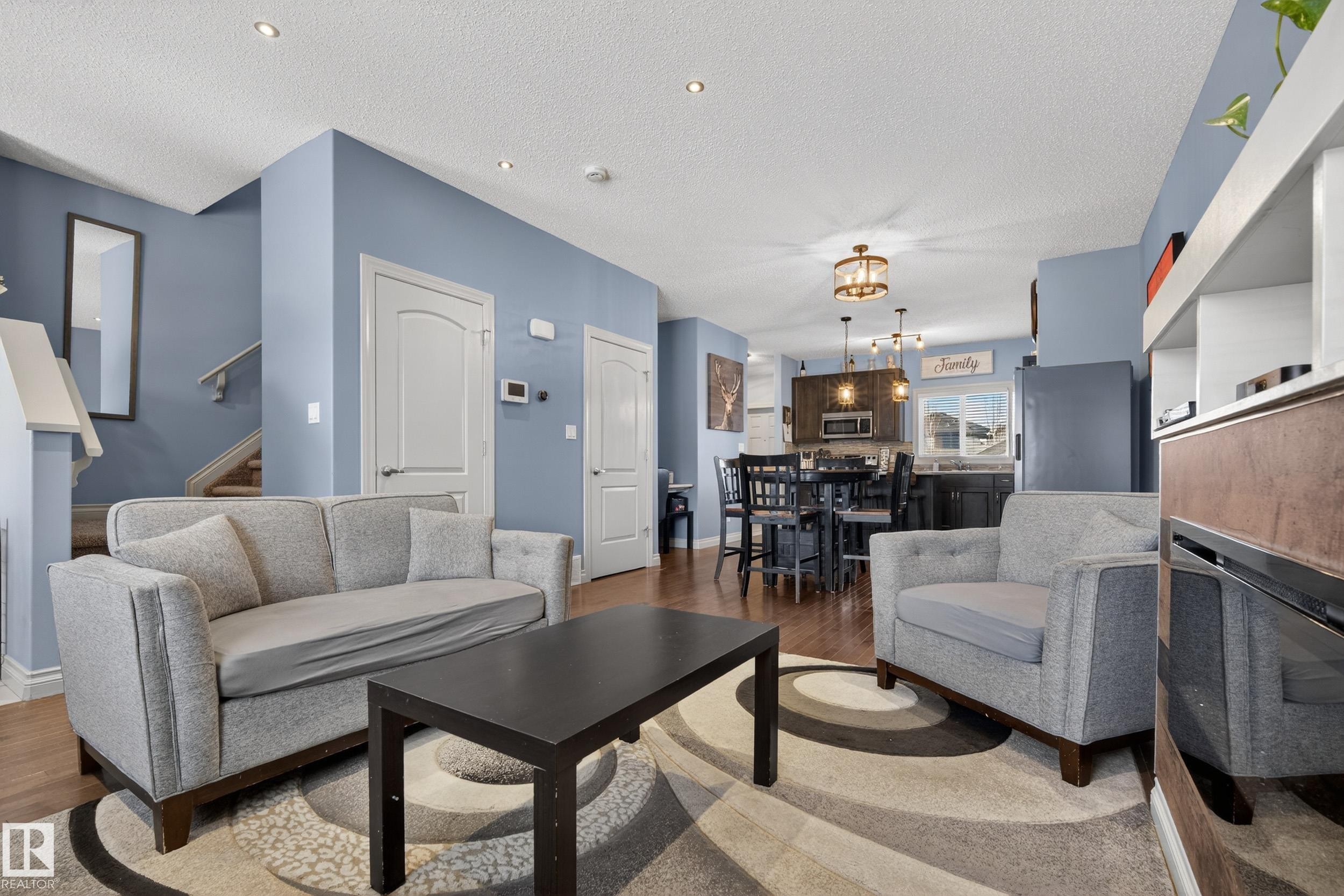 Open-concept living space featuring wood-finish flooring and light blue walls - 7074 Cardinal Way, Edmonton, AB - Indoor Photo Showing Living Room
