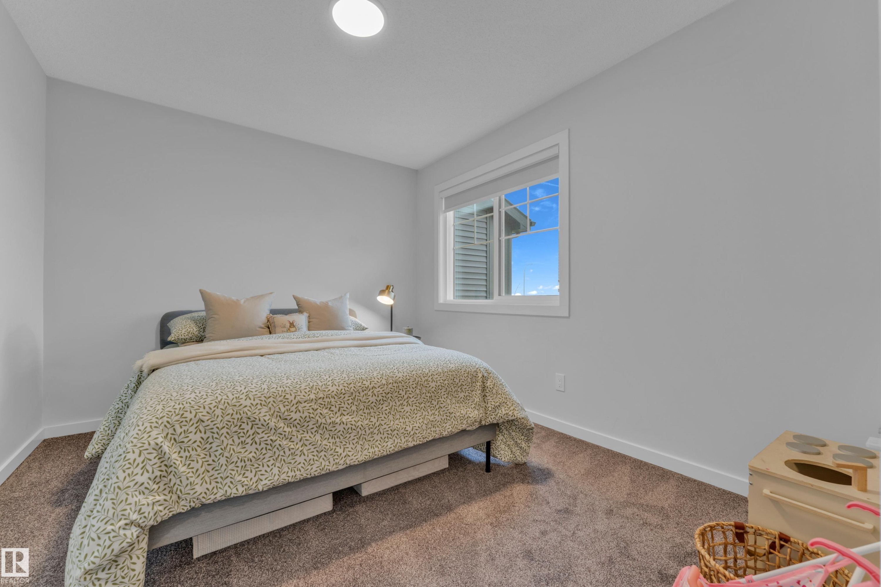Bright interior space featuring a window with white trim, a flush-mount ceiling light, and neutral wall paint - 17319 2 St Nw, Edmonton, AB - Indoor Photo Showing Bedroom