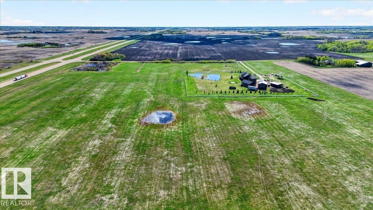 This property features a substantial main residence with a prominent dark-colored roof, surrounded by expansive snow-covered grounds - 531064 Range Road 174, Rural Lamont County, AB - Outdoor With Body Of Water With View