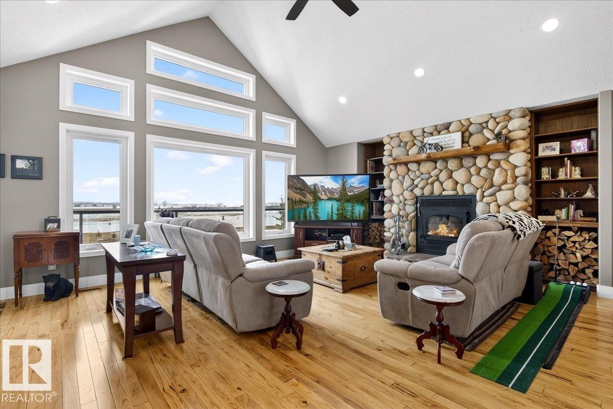 Open concept living space featuring a vaulted ceiling with a ceiling fan, light hardwood flooring, and a stone fireplace - 531064 Range Road 174, Rural Lamont County, AB - Indoor Photo Showing Living Room