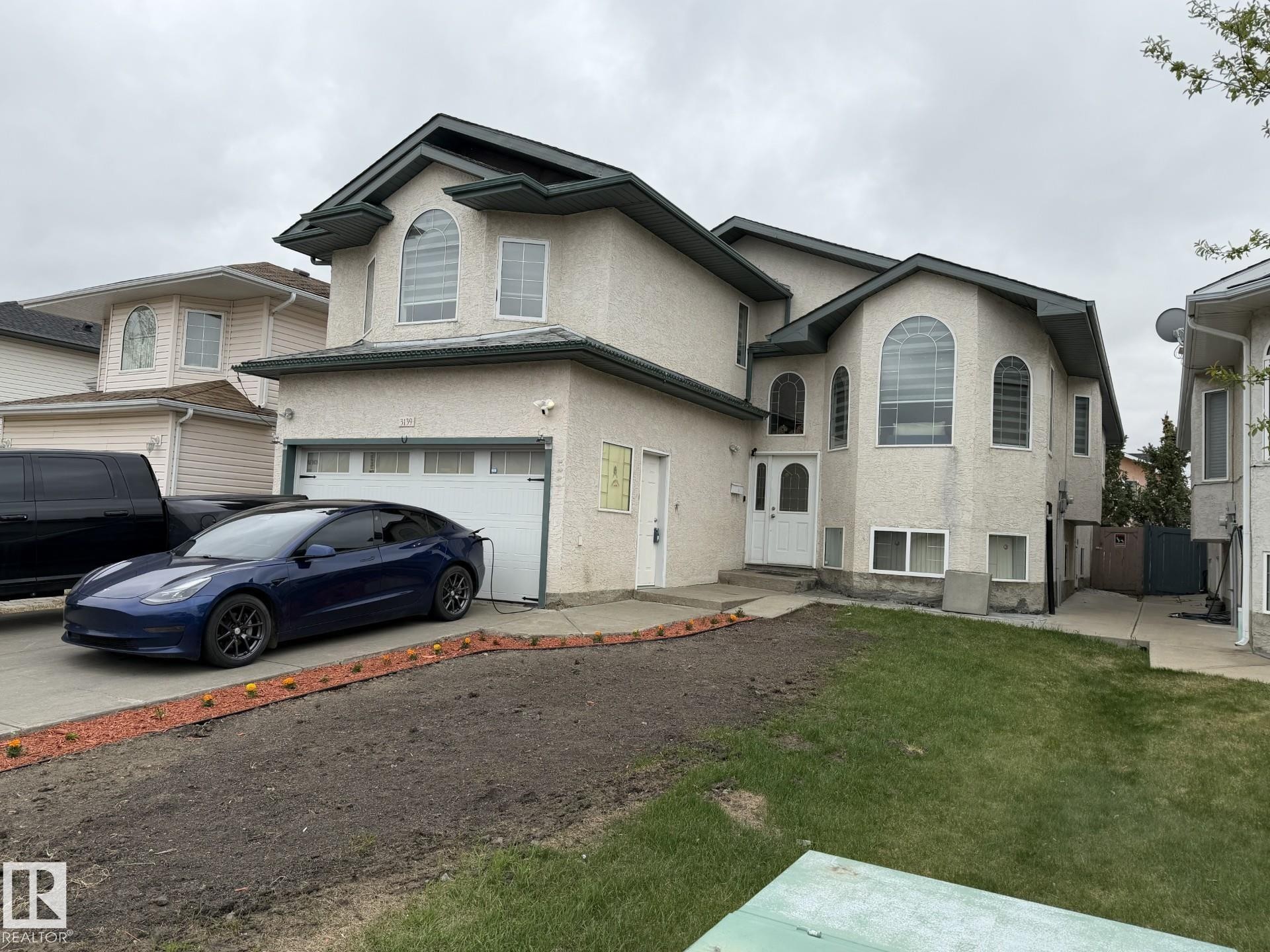 Stucco exterior with arched windows, an integrated single-car garage, and a front entry with a sidelight - 3139 34B Avenue, Edmonton, AB - Outdoor With Facade