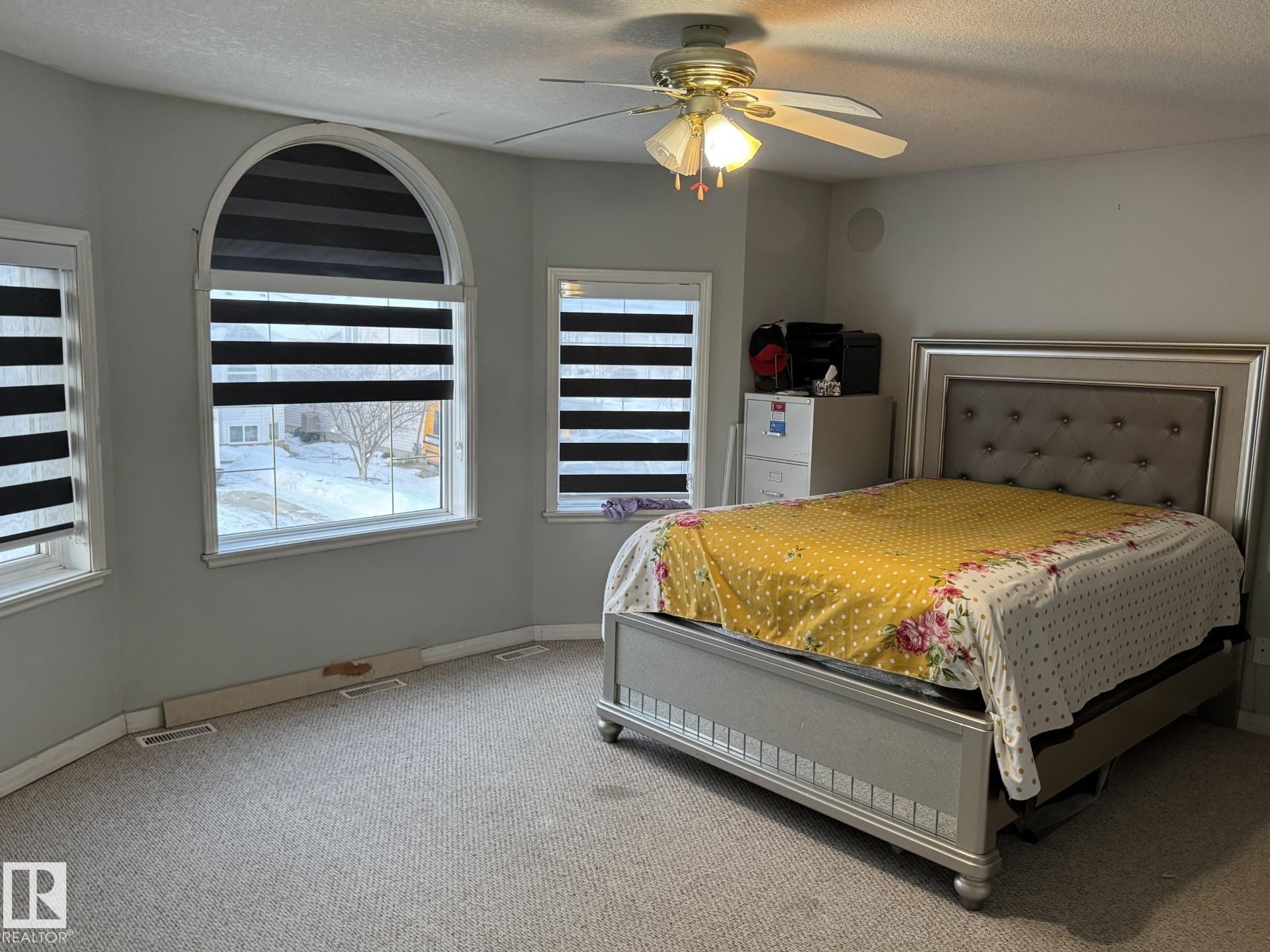 Carpeted room featuring an arched window, two additional rectangular windows, and a ceiling fan with integrated lighting - 3139 34B Avenue, Edmonton, AB - Indoor Photo Showing Bedroom