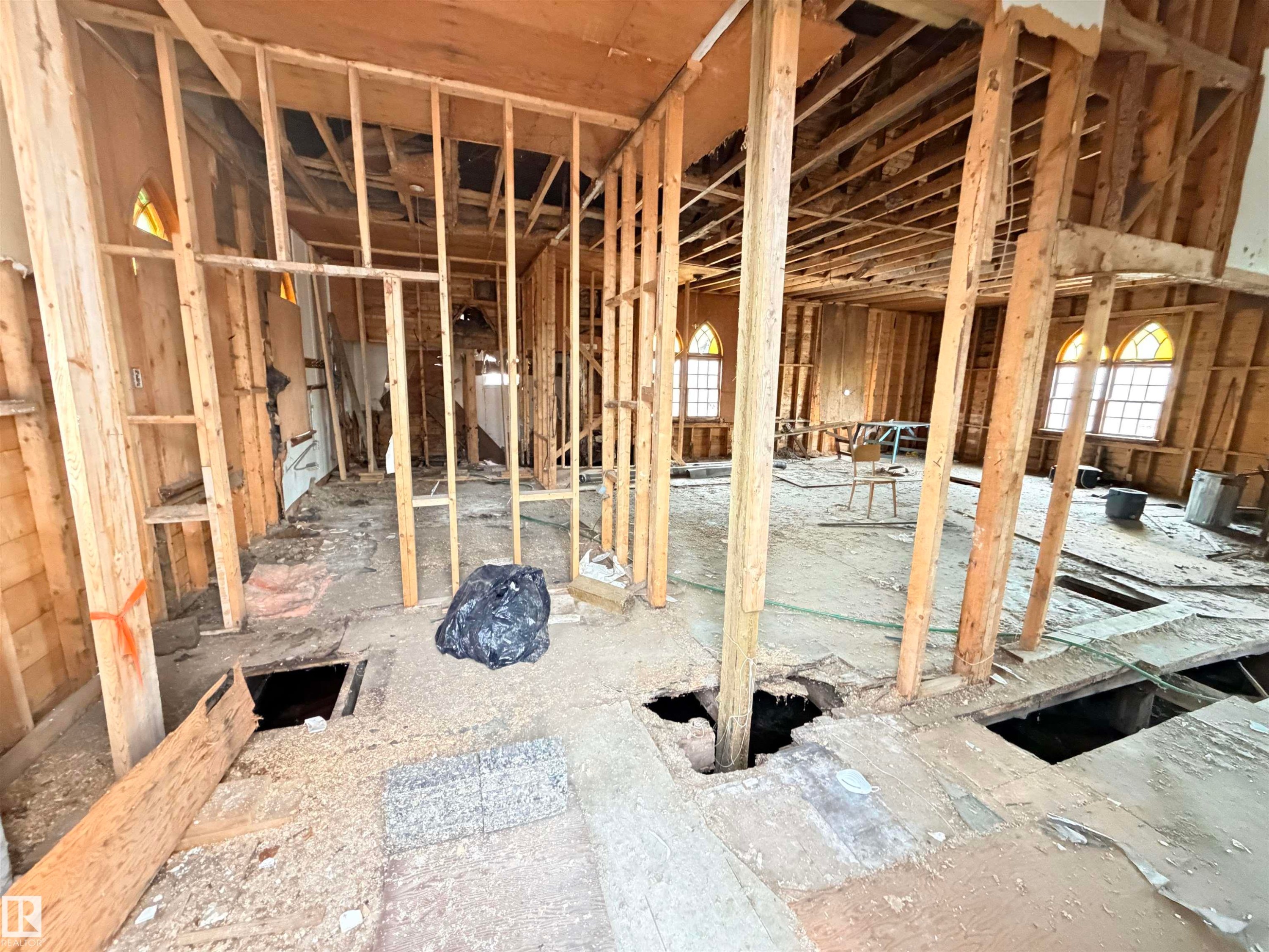 Framed interior structure with visible joists and framing, arched windows, and exposed subflooring - 5036 49 Street, Clyde, AB - Indoor