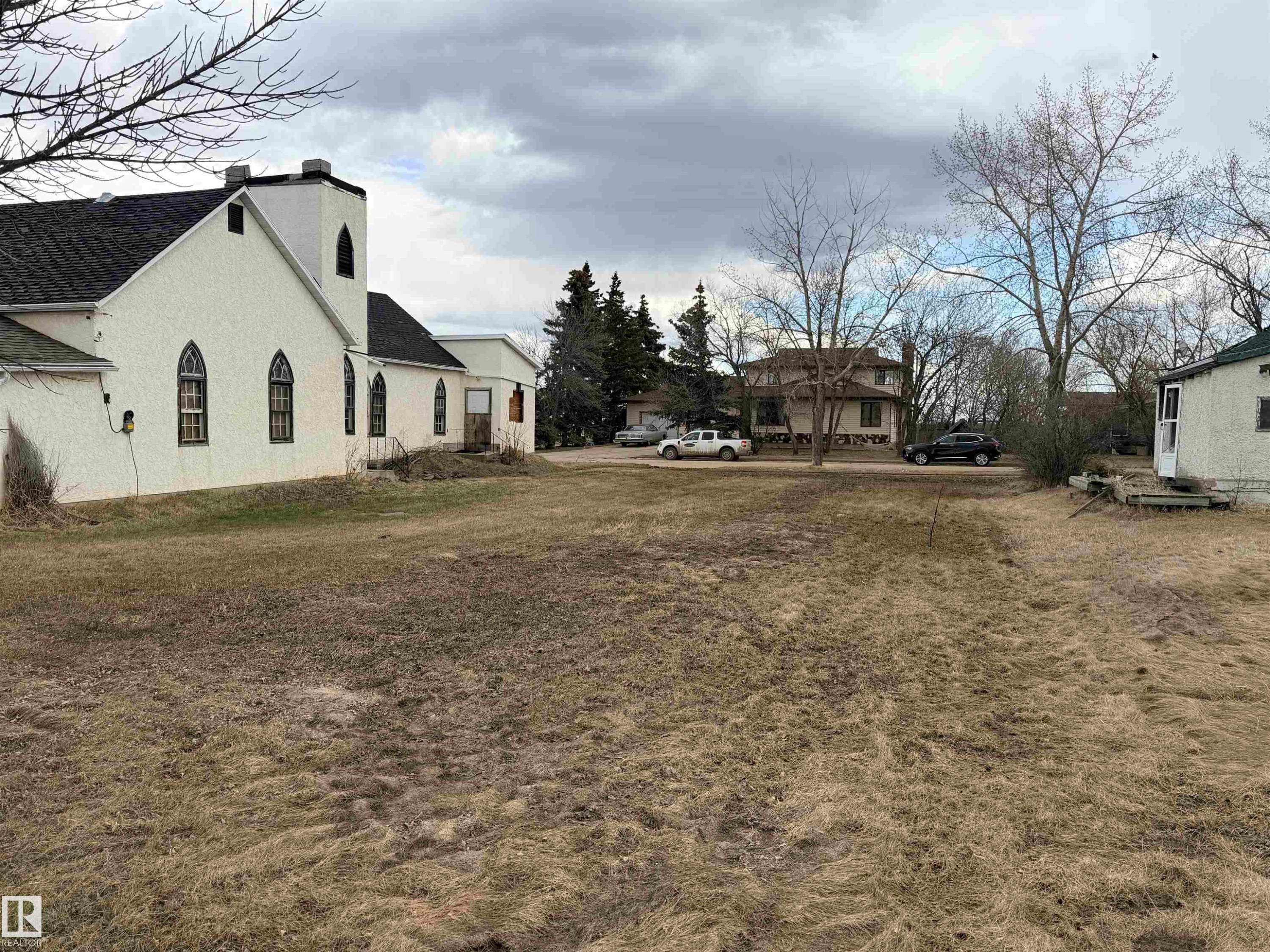 Building with white stucco exterior and black-trimmed arched windows - 5036 49 Street, Clyde, AB - Outdoor
